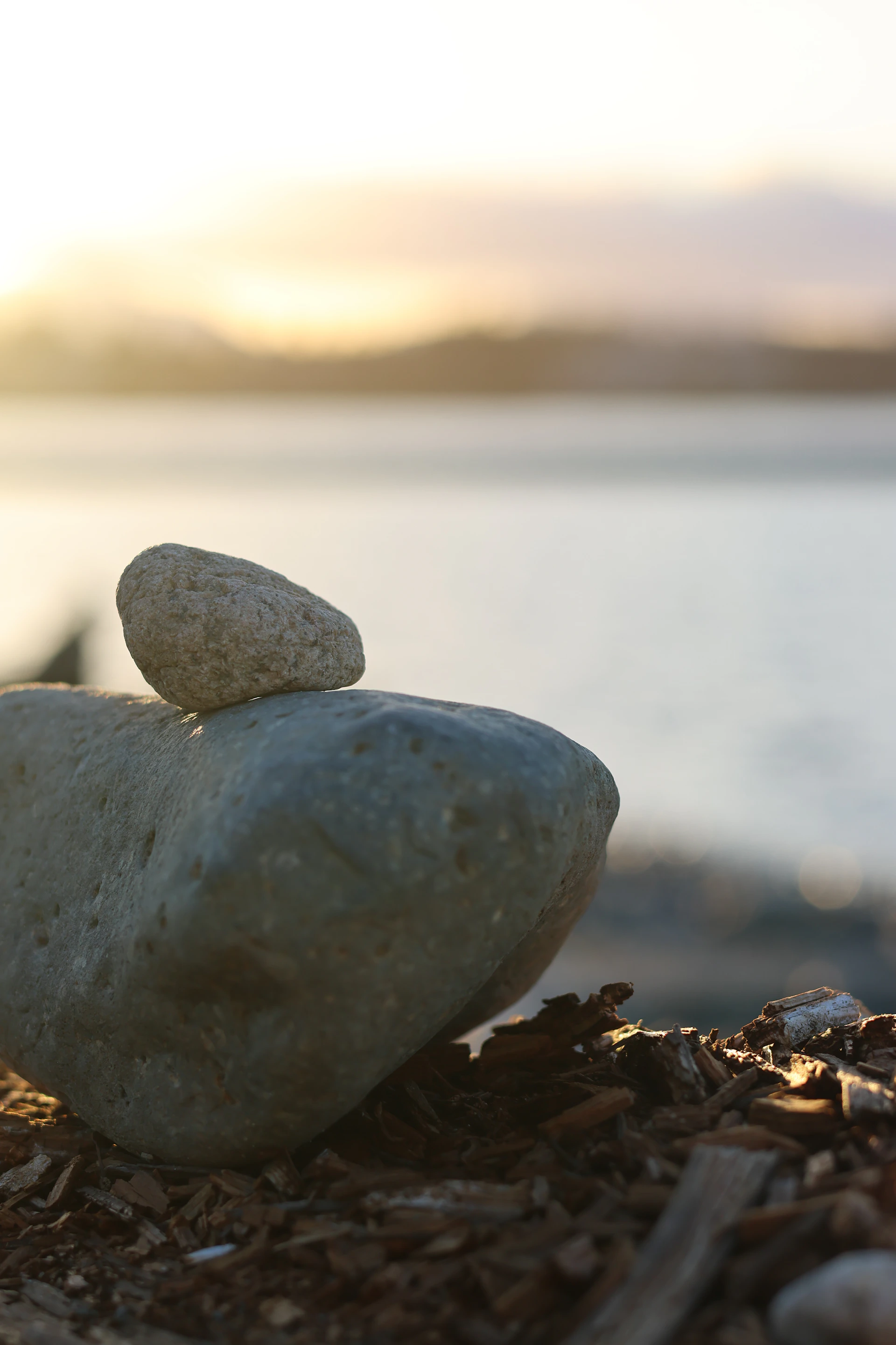 Two stones stacked on a beach at sunset.
