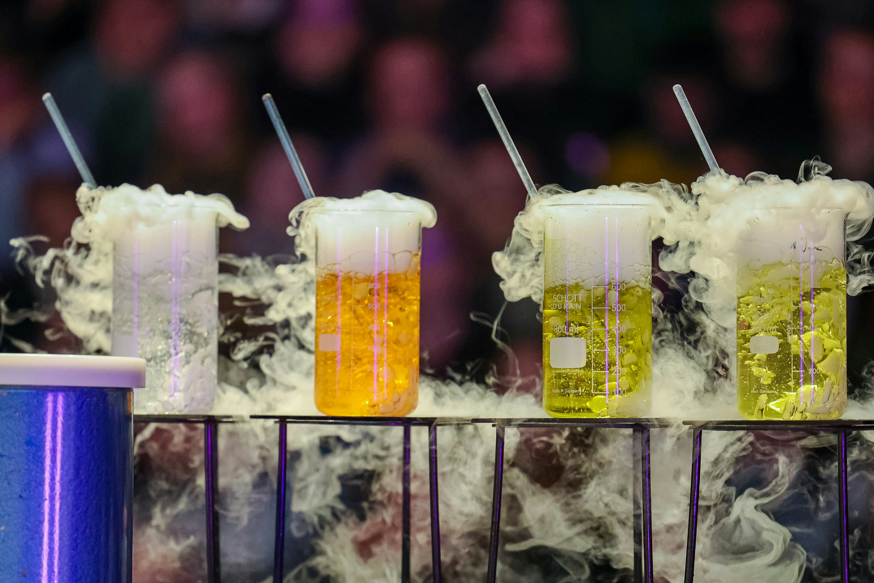 Four beakers with bubbling liquids and smoke