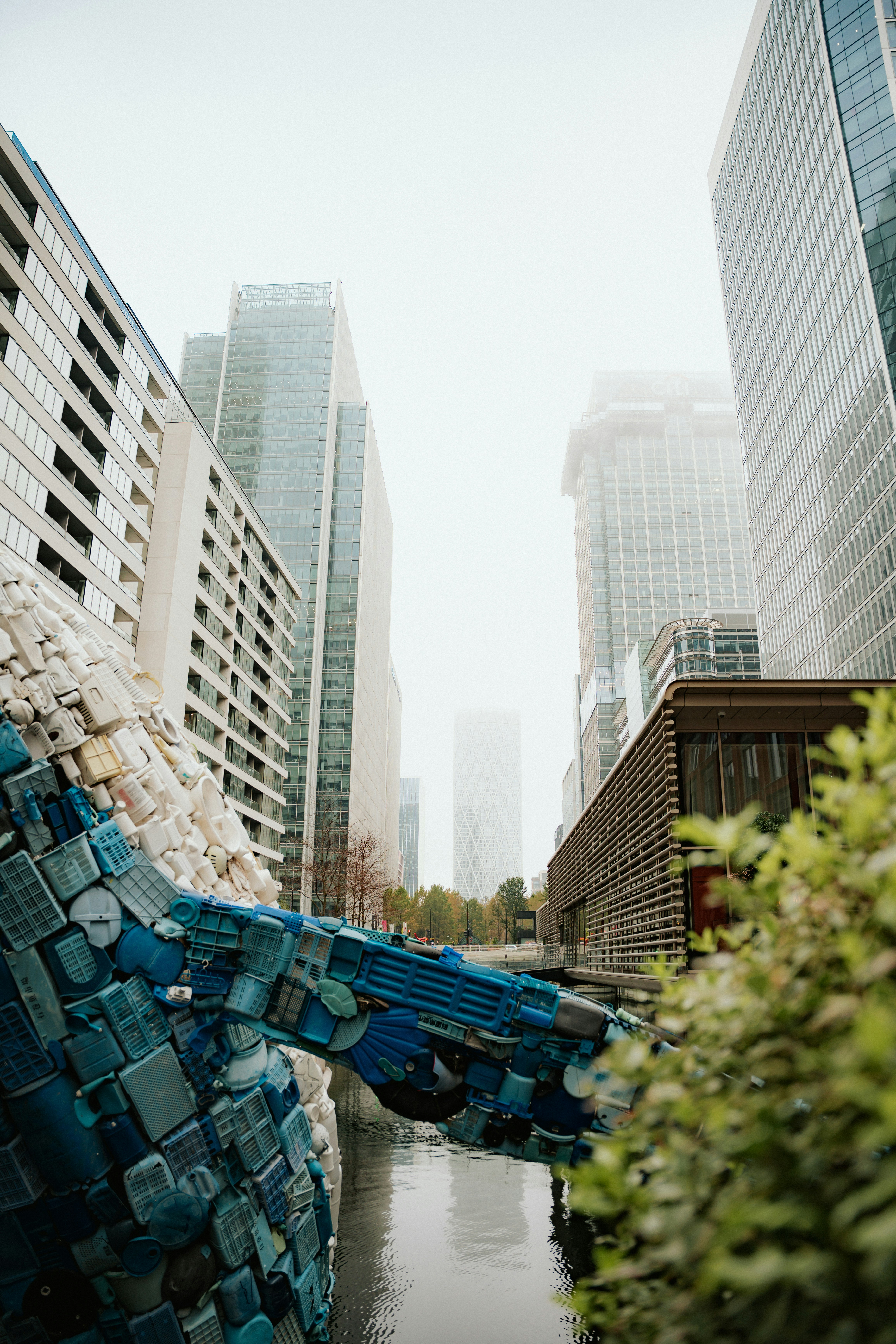 Sculpture made of blue plastic bottles in urban canal.