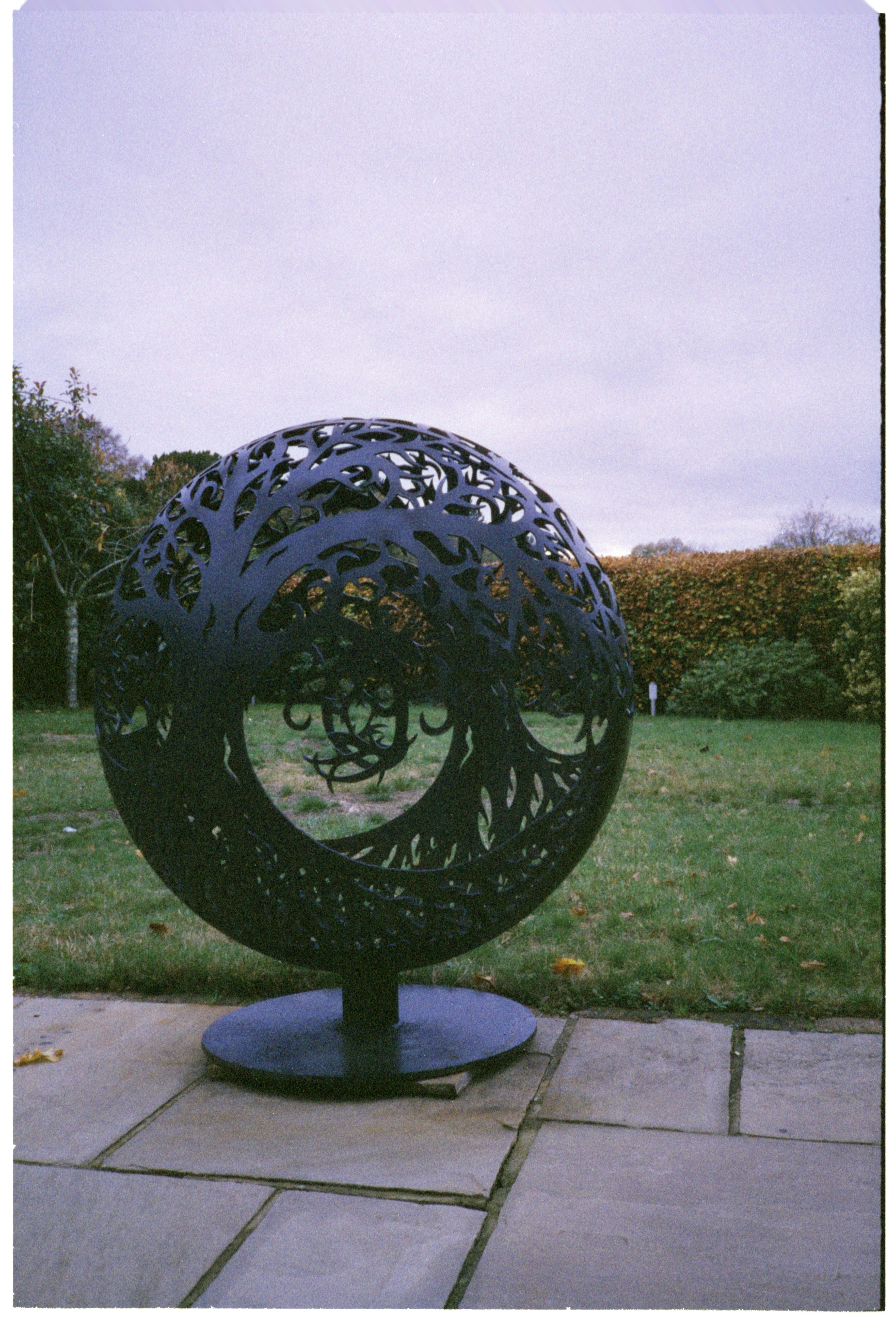 Ornate metal sphere sculpture in a garden setting