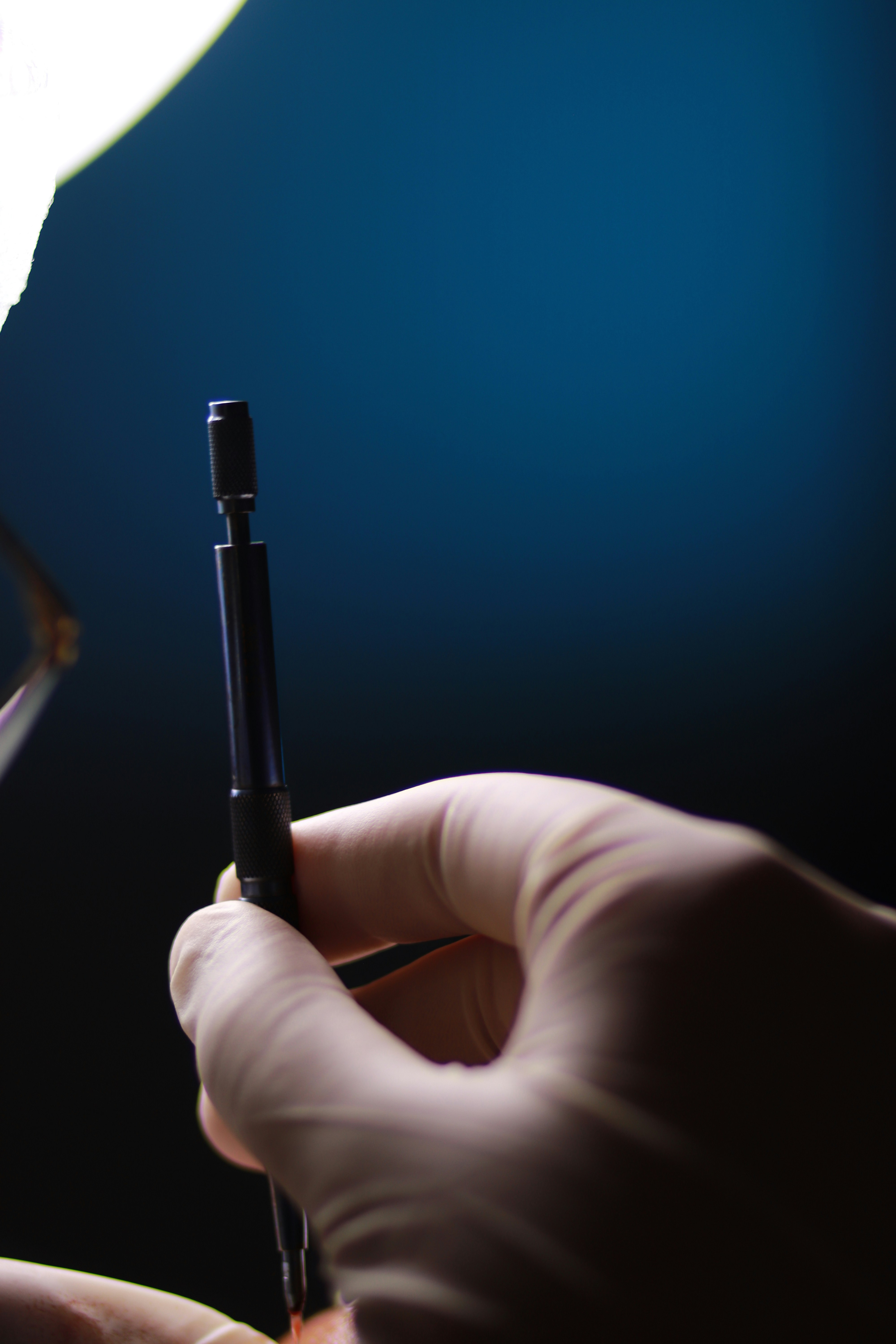 Gloved hand holding a surgical instrument.