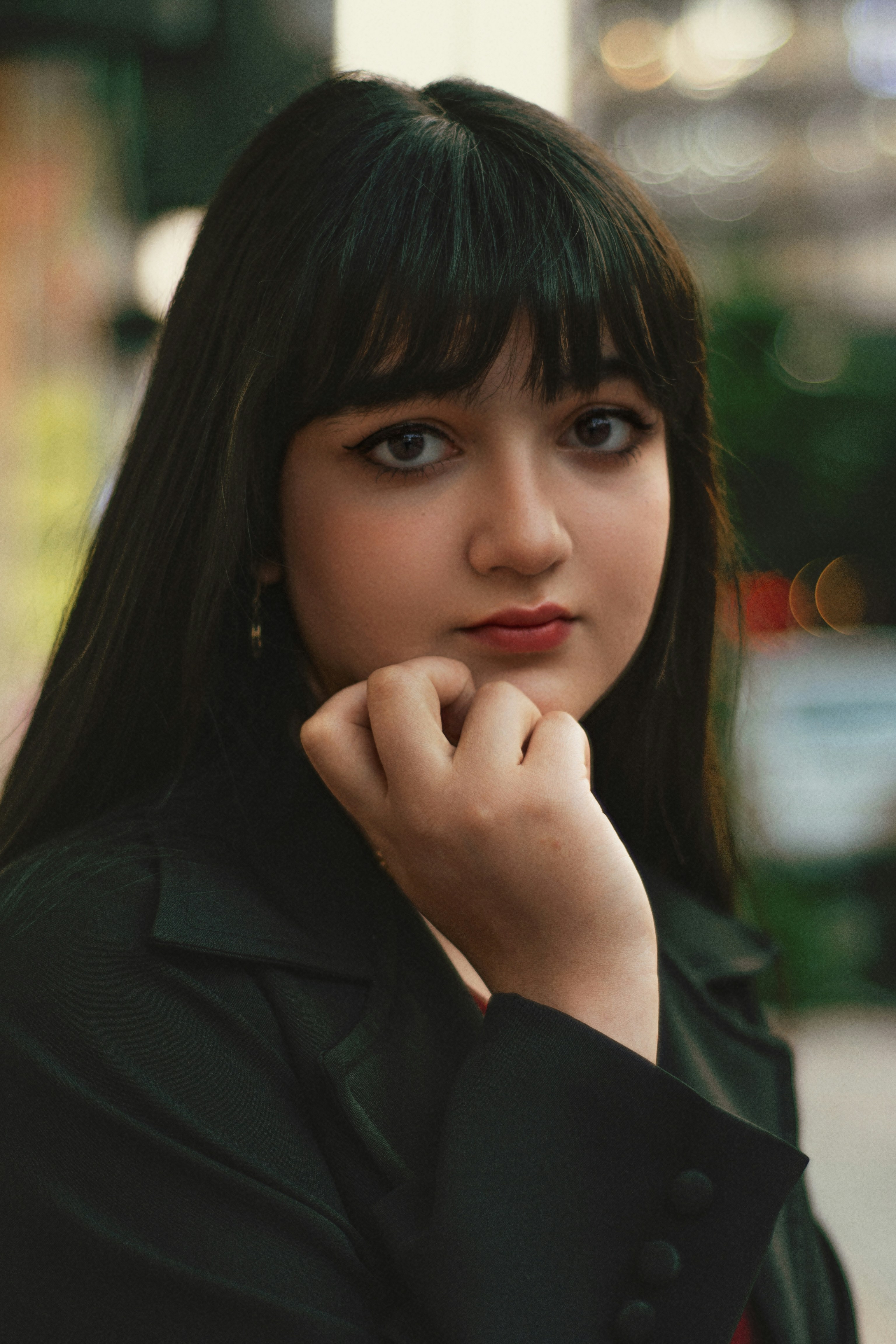 Young woman with dark hair and bangs looks forward.