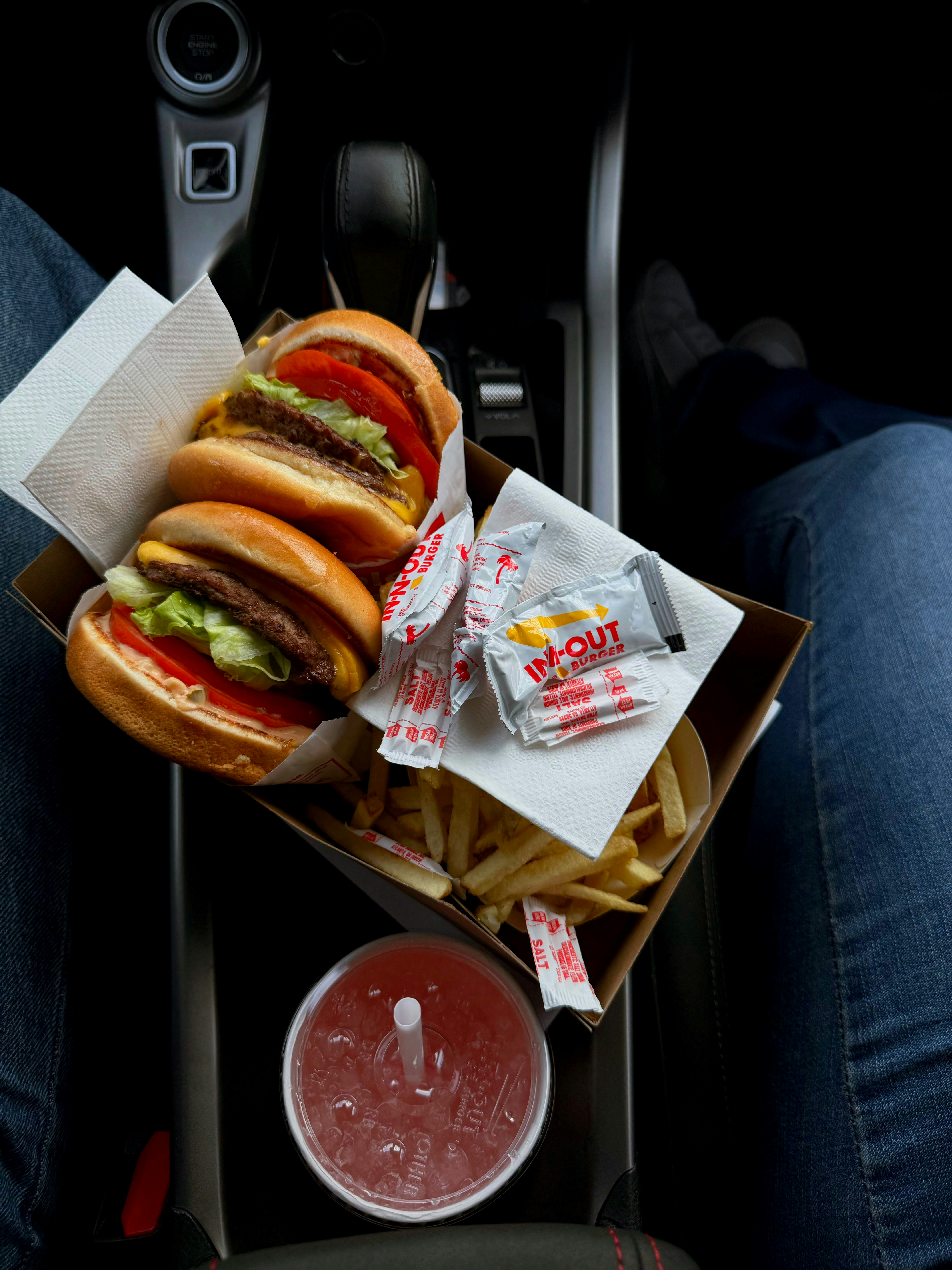 How to Eat Well on a Road Trip Without Fast Food or Coolers – Two burgers, fries, and a drink in a car.