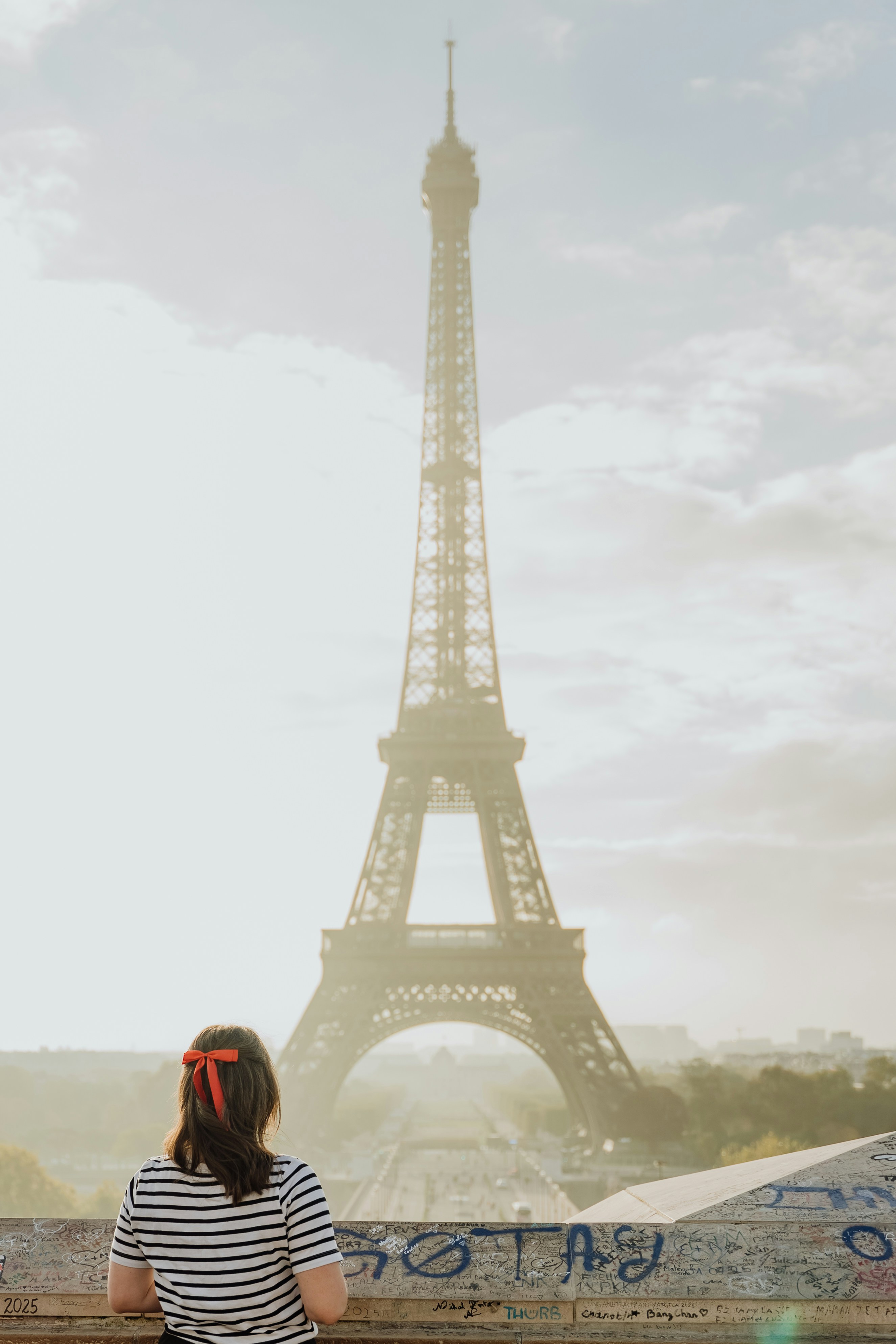 Woman with red bow admires eiffel tower in paris