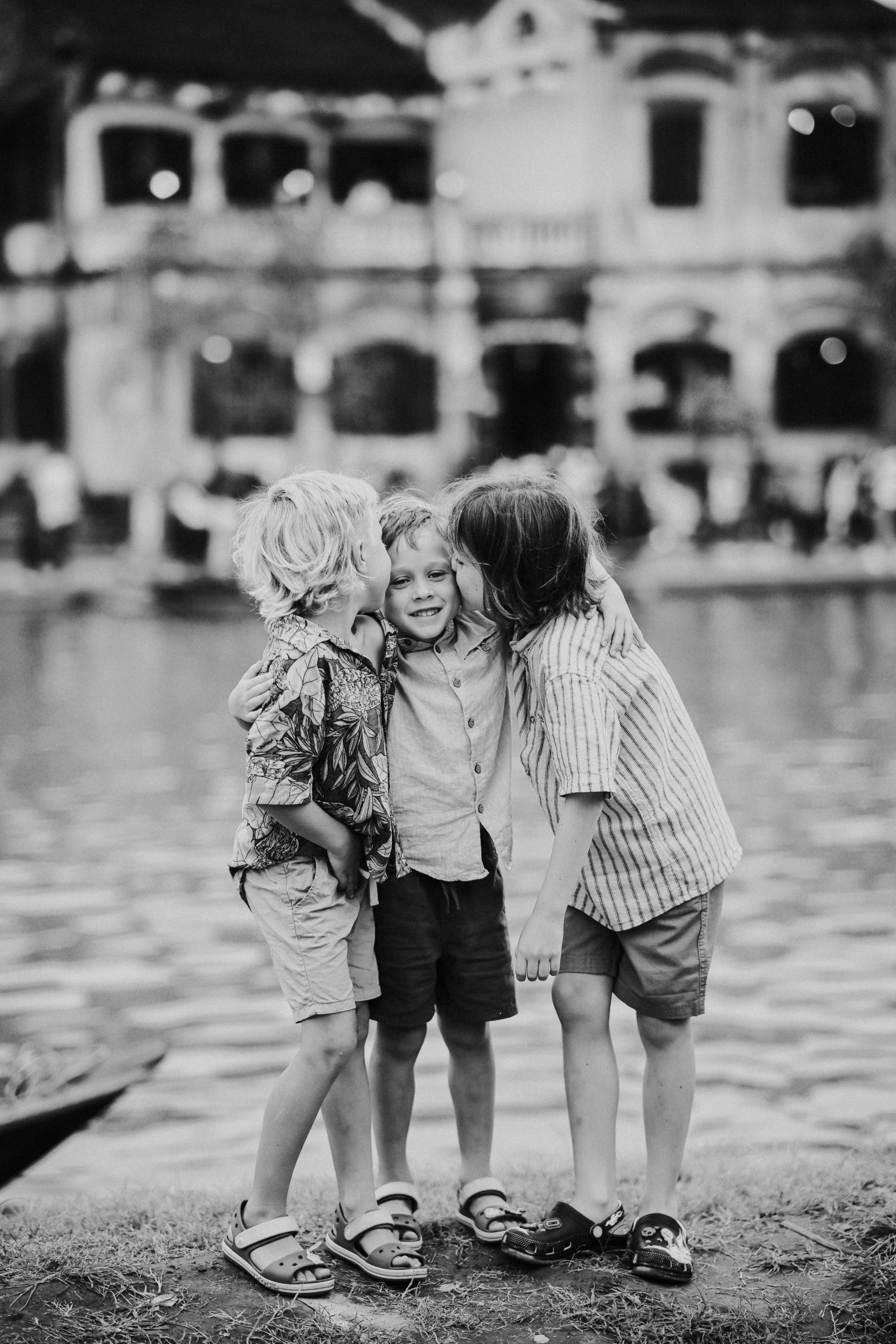 Three children sharing a tender moment by the water.