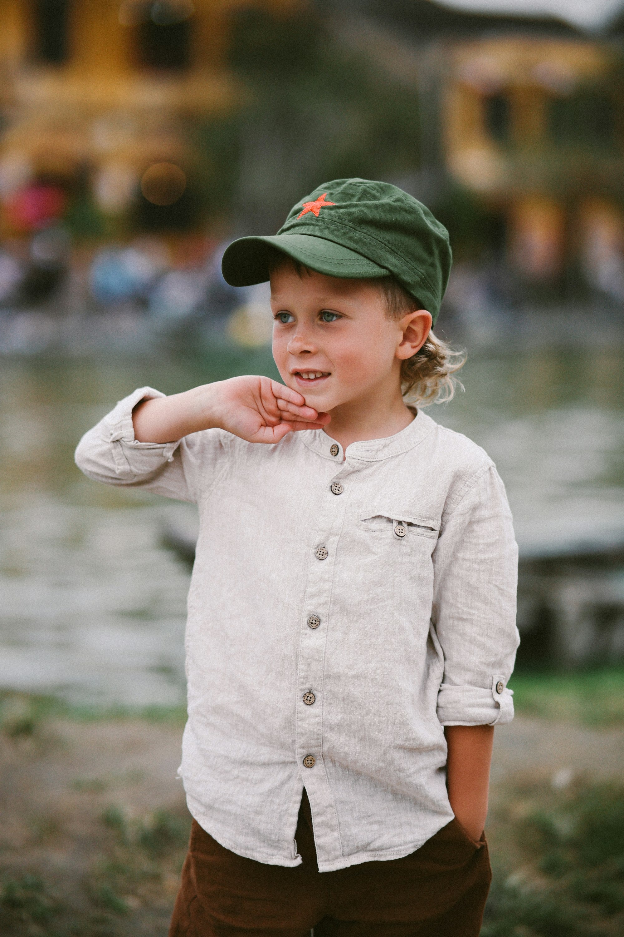 Young boy wearing a green cap and linen shirt.