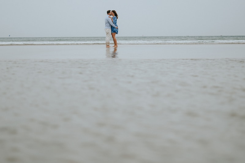 Gay couple embracing on wet sandy beach
