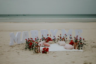 Beach proposal setup with marry me letters and roses