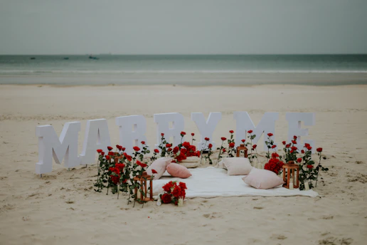 Beach proposal setup with marry me letters and roses