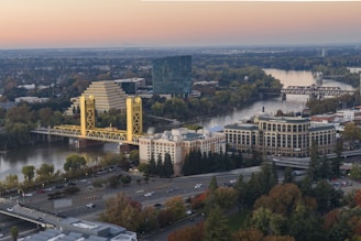 City skyline with a river and bridge at sunset.
