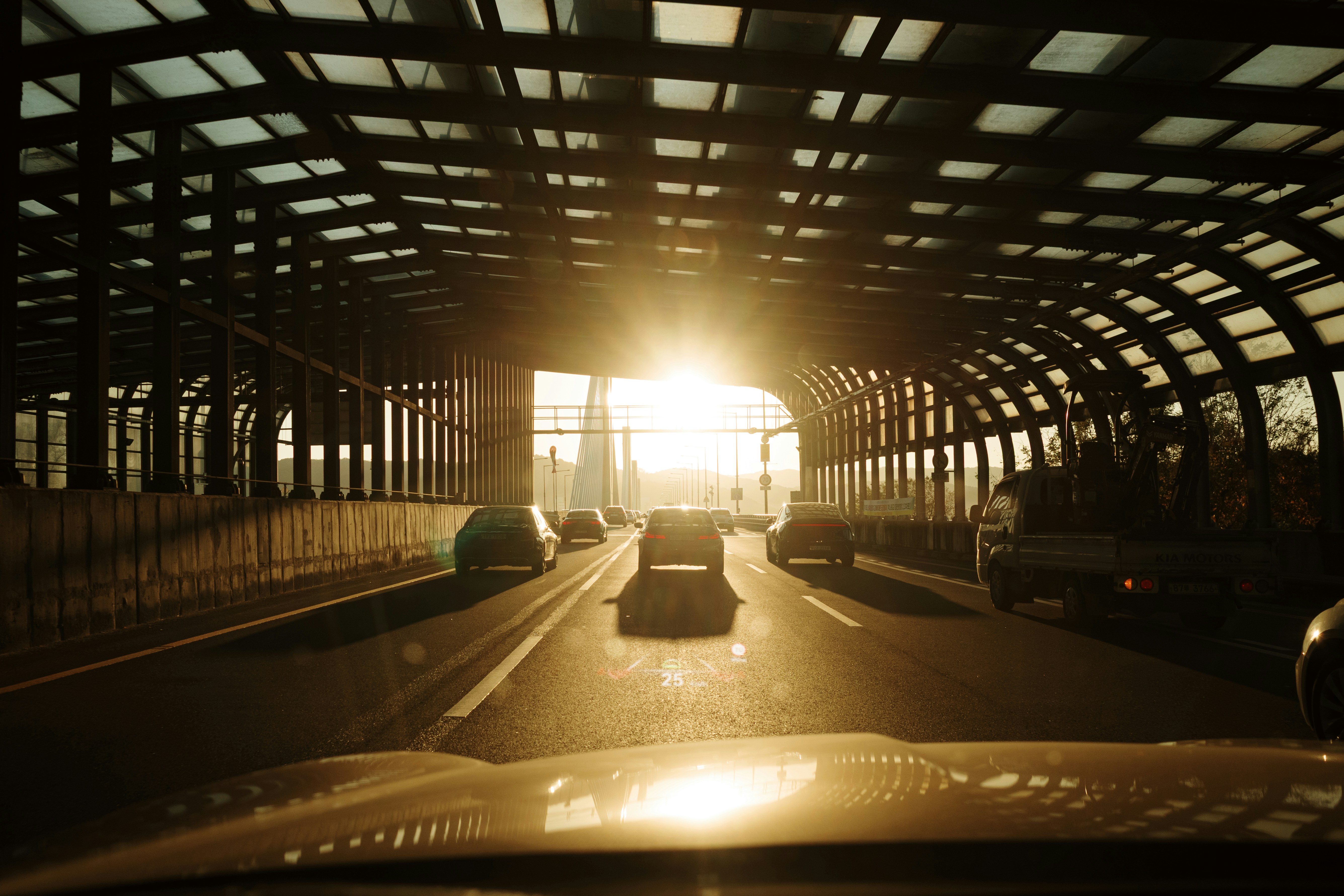 Cars driving towards the sunlit tunnel exit.