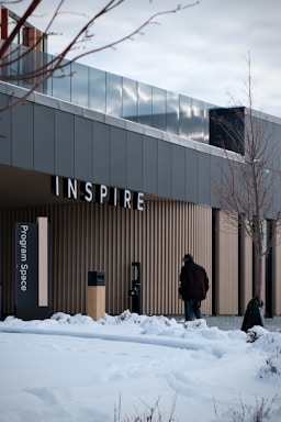 Man walks towards building with "inspire" sign.