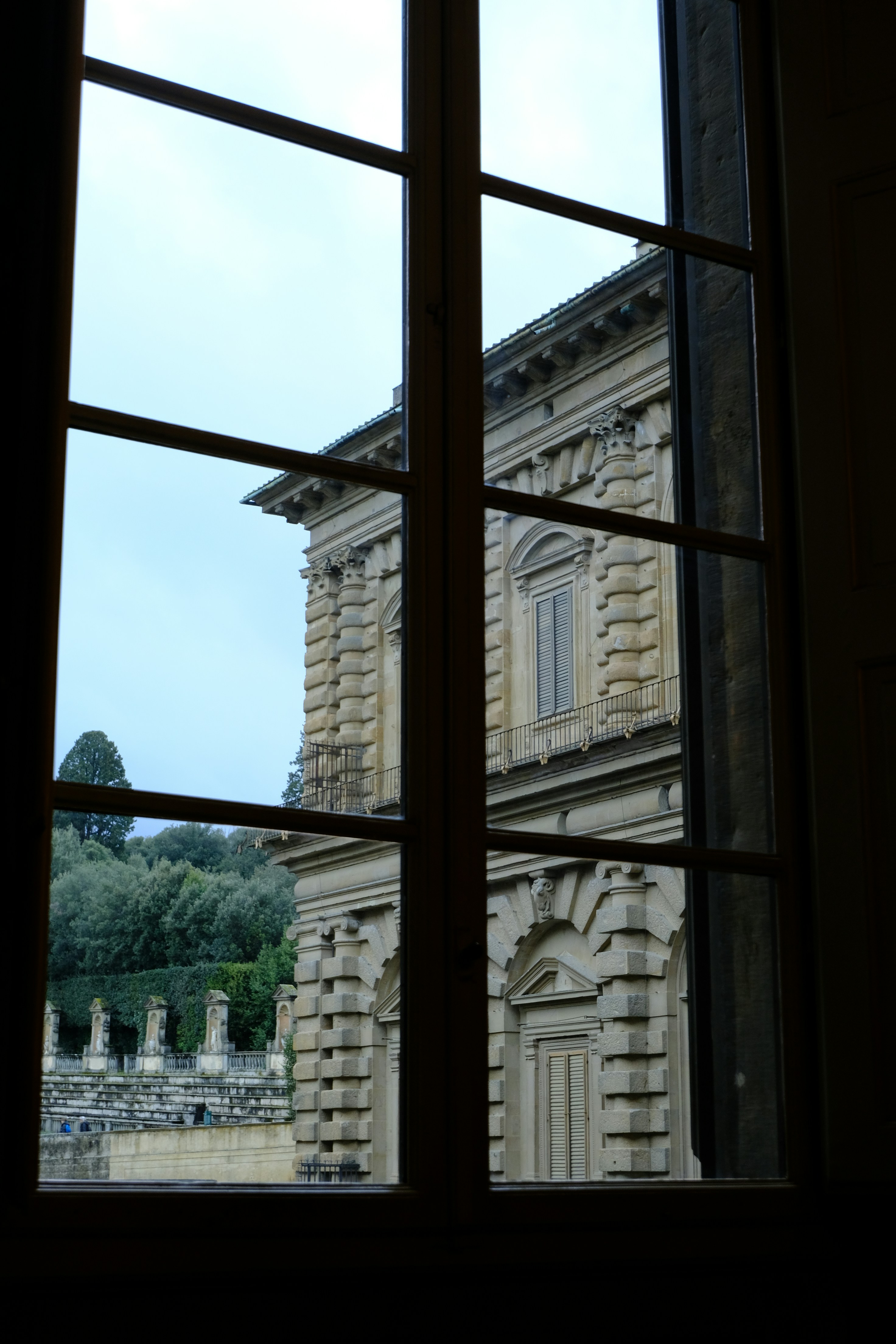 Ornate building viewed through a window with garden