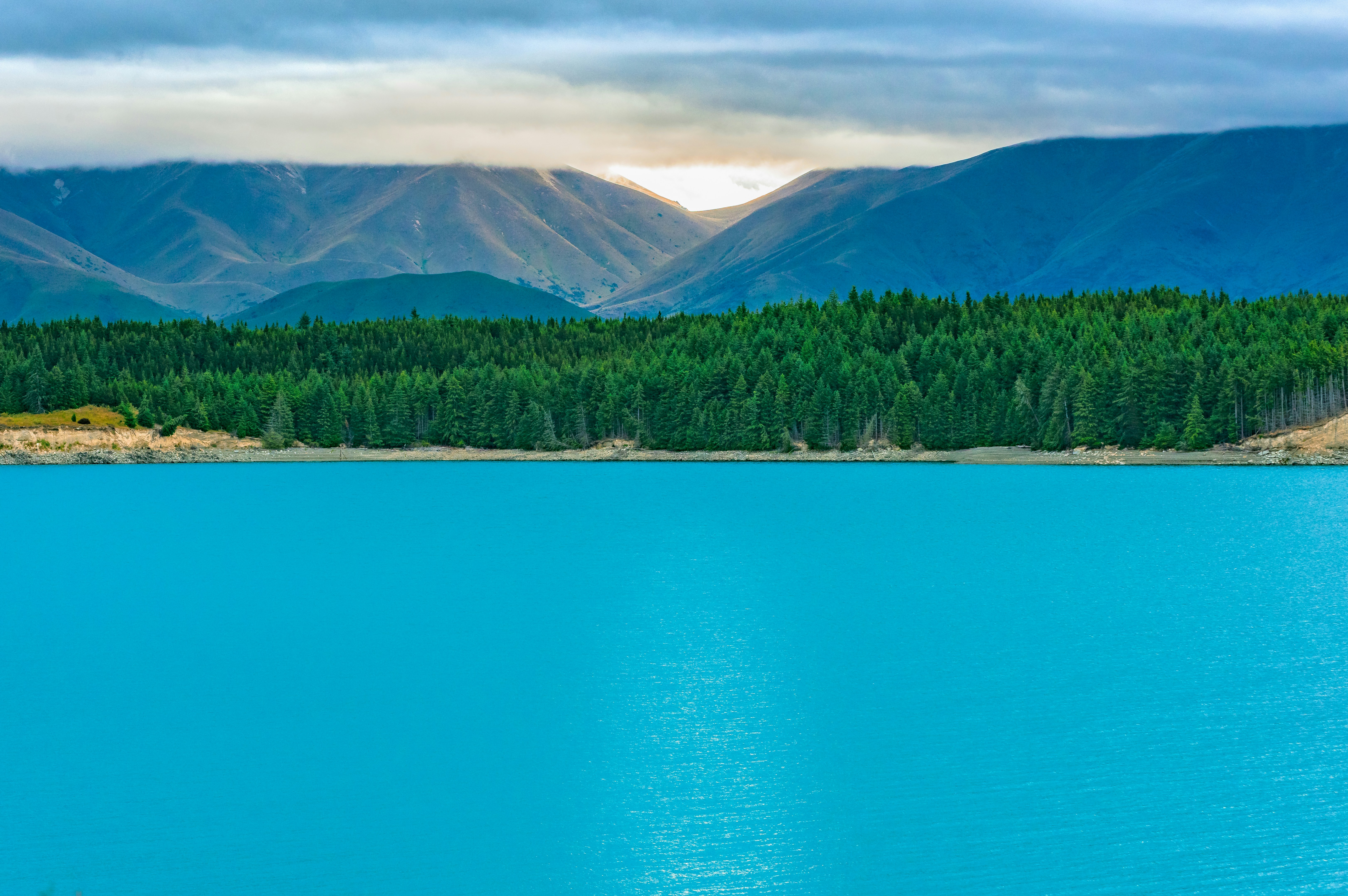 Vibrant blue lake with green forest and mountains