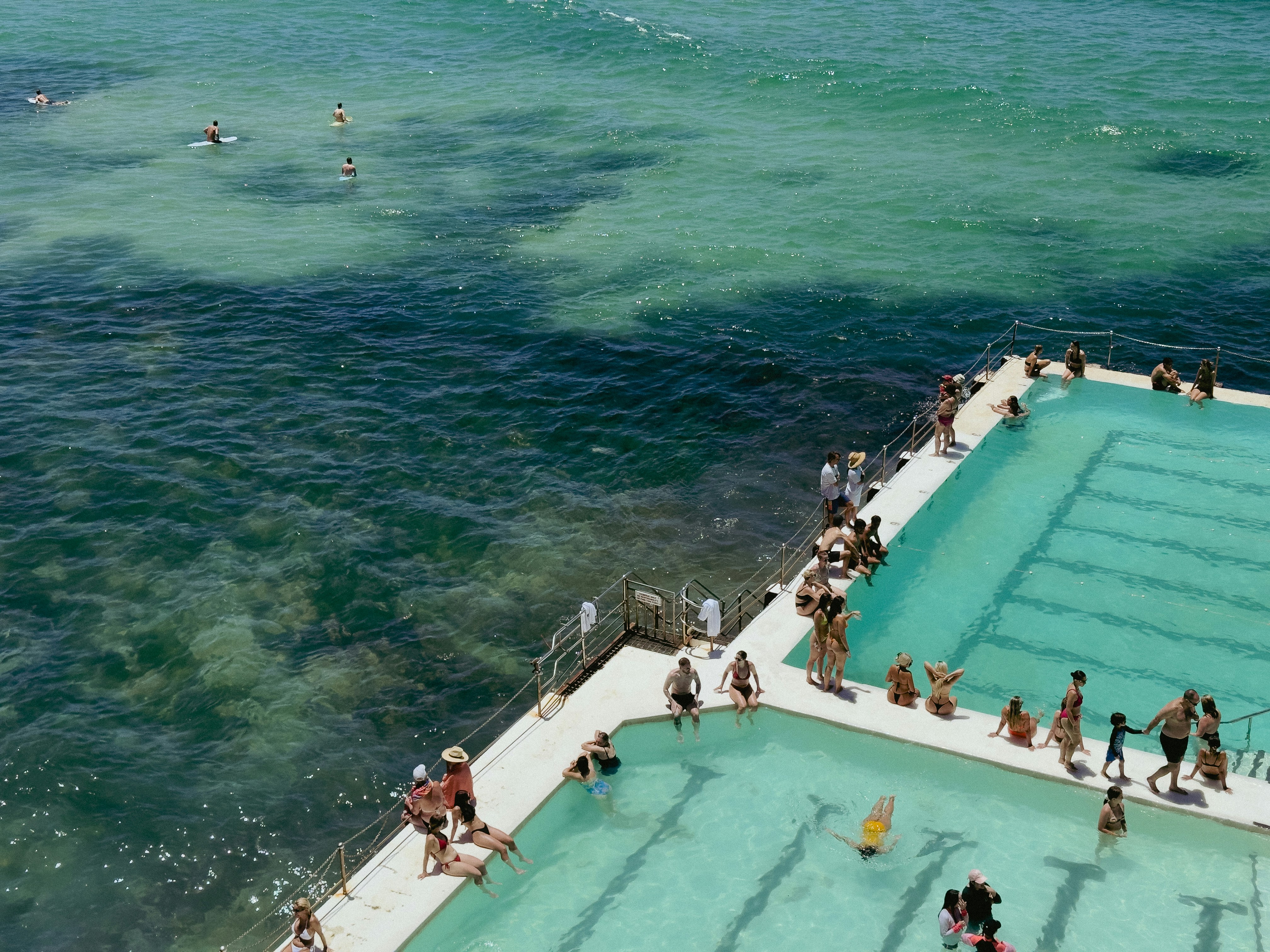 Des gens nagent dans une piscine océanique au bord de la mer