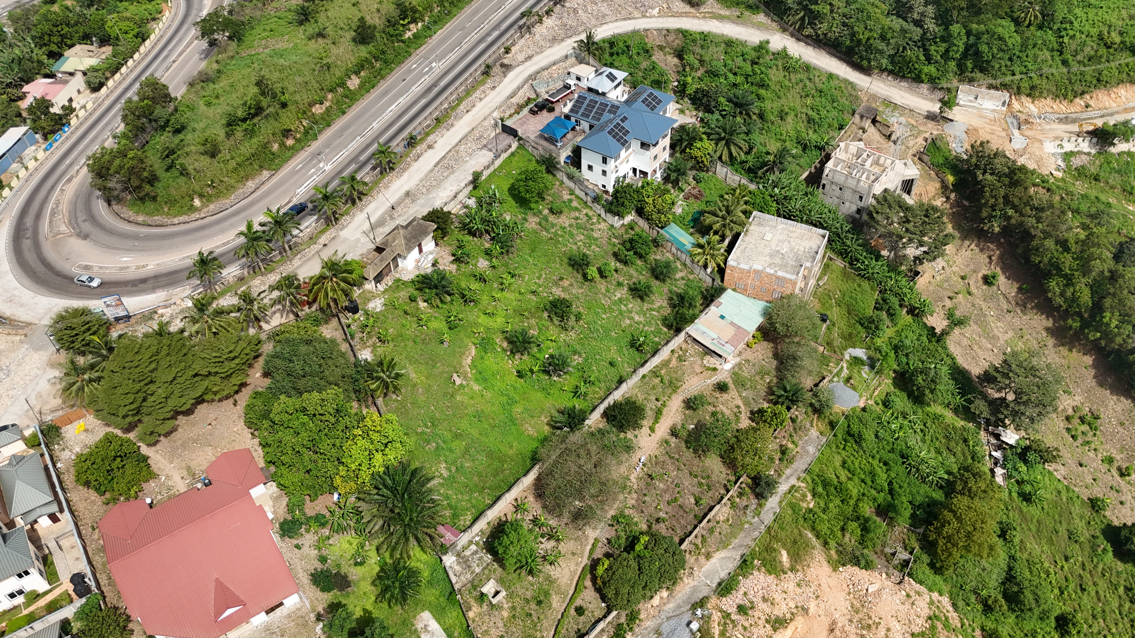 Aerial view of a hillside with plots, houses and roads
