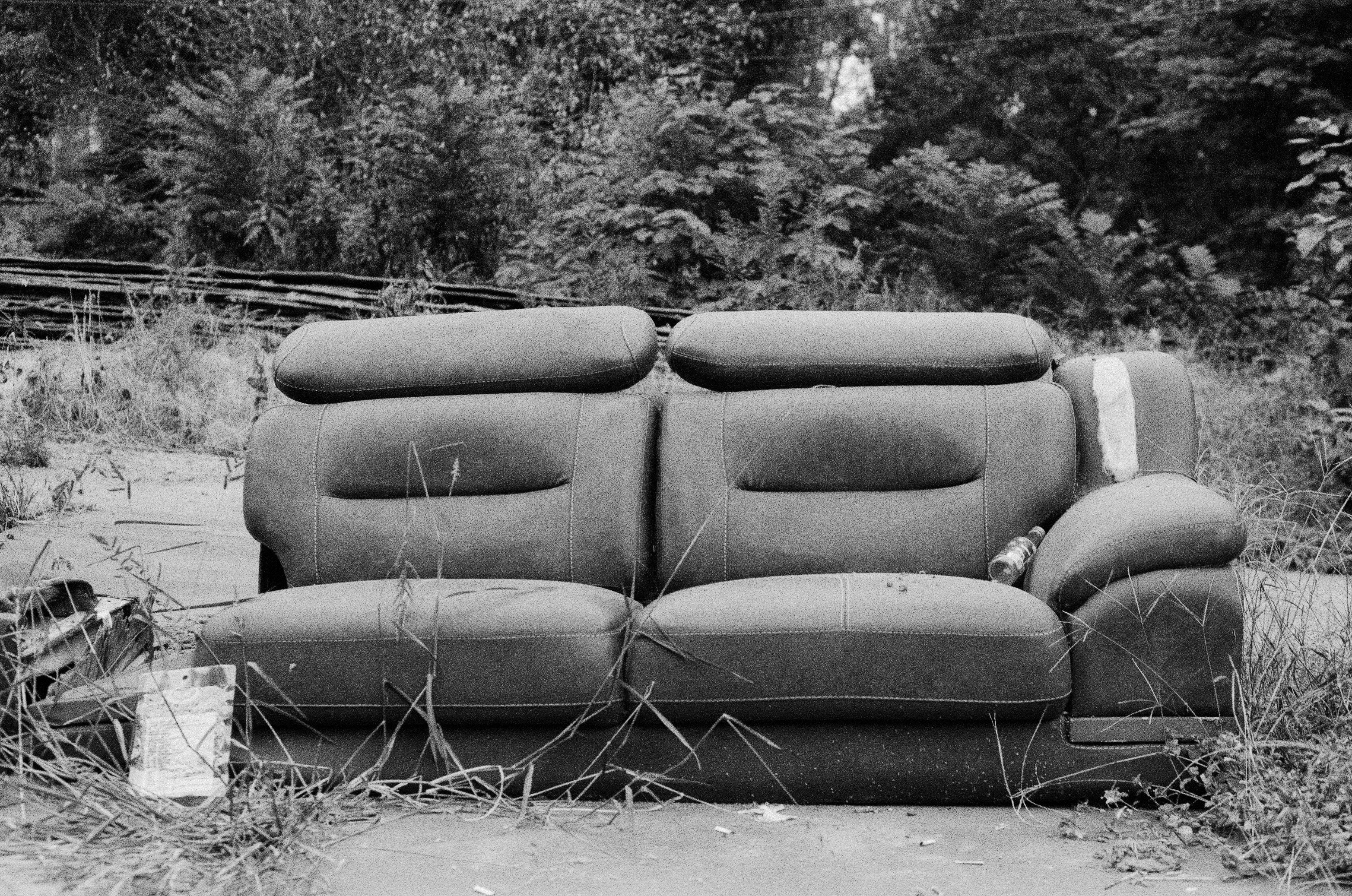 古いソファが雑草の中に放置されている。