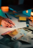 Hand writing on paper with euro banknotes and dollar bills.
