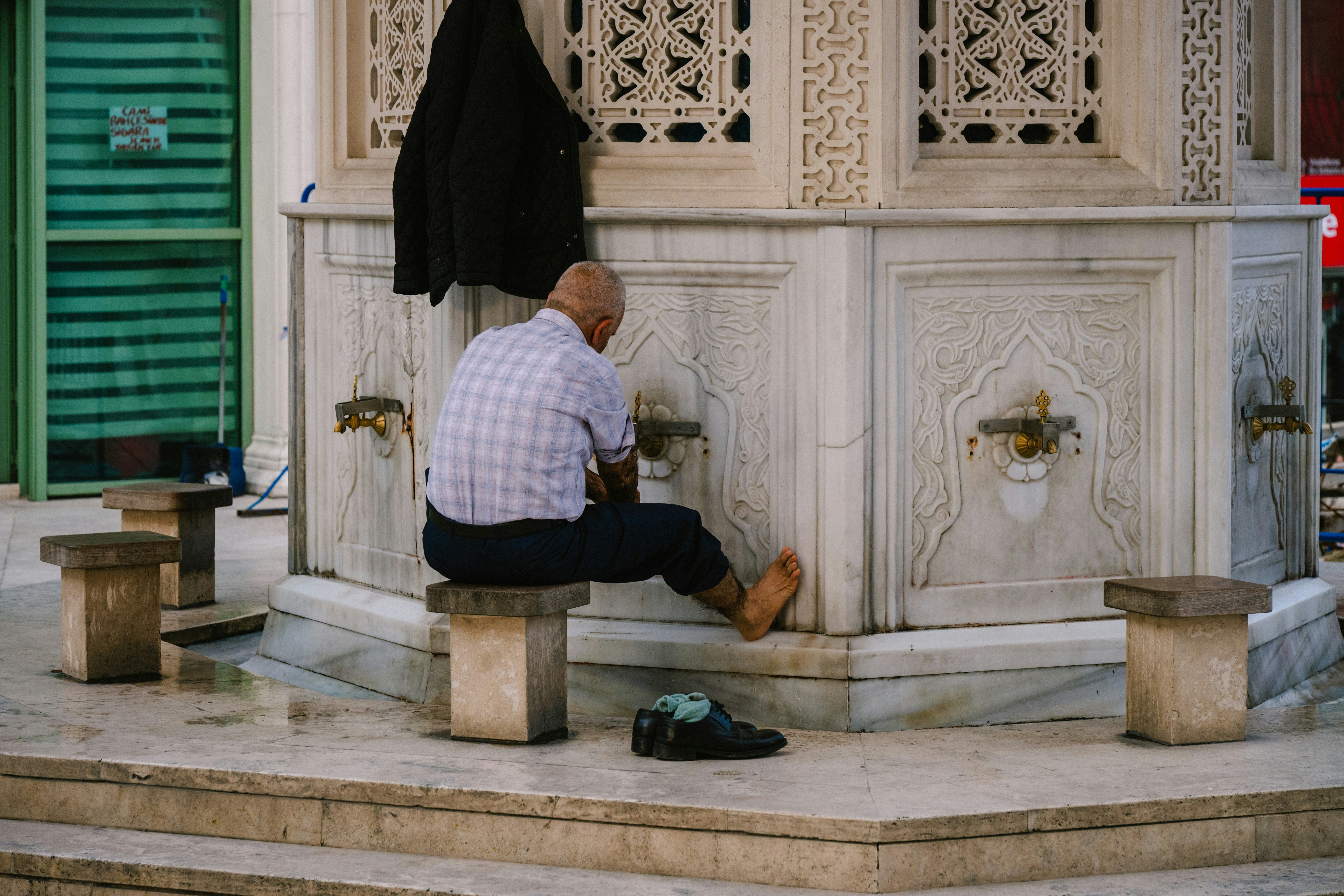 Man performs ablution at a marble fountain