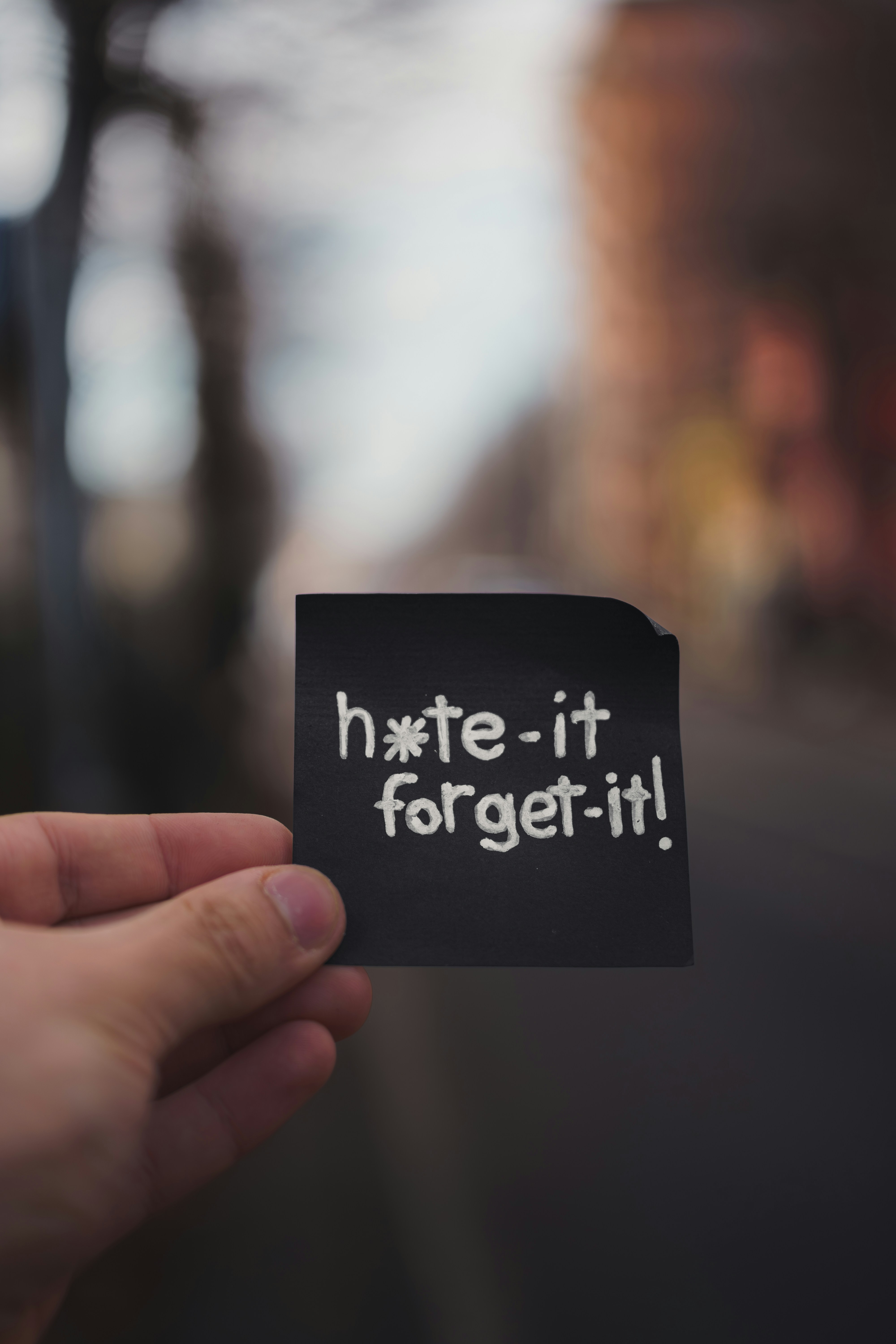 Mão segurando um post-it preto com texto.