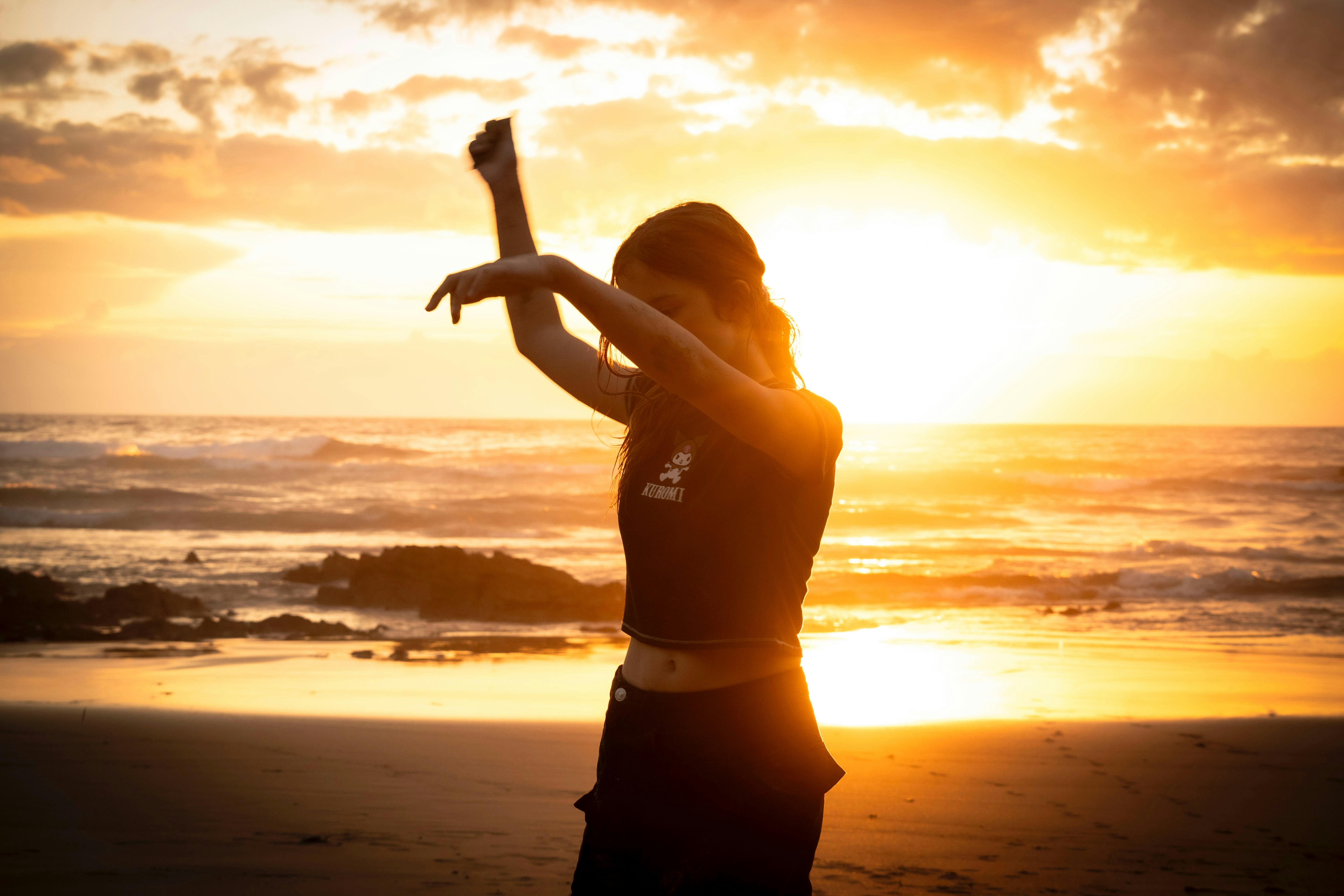 Frau, die am Strand bei Sonnenuntergang tanzt