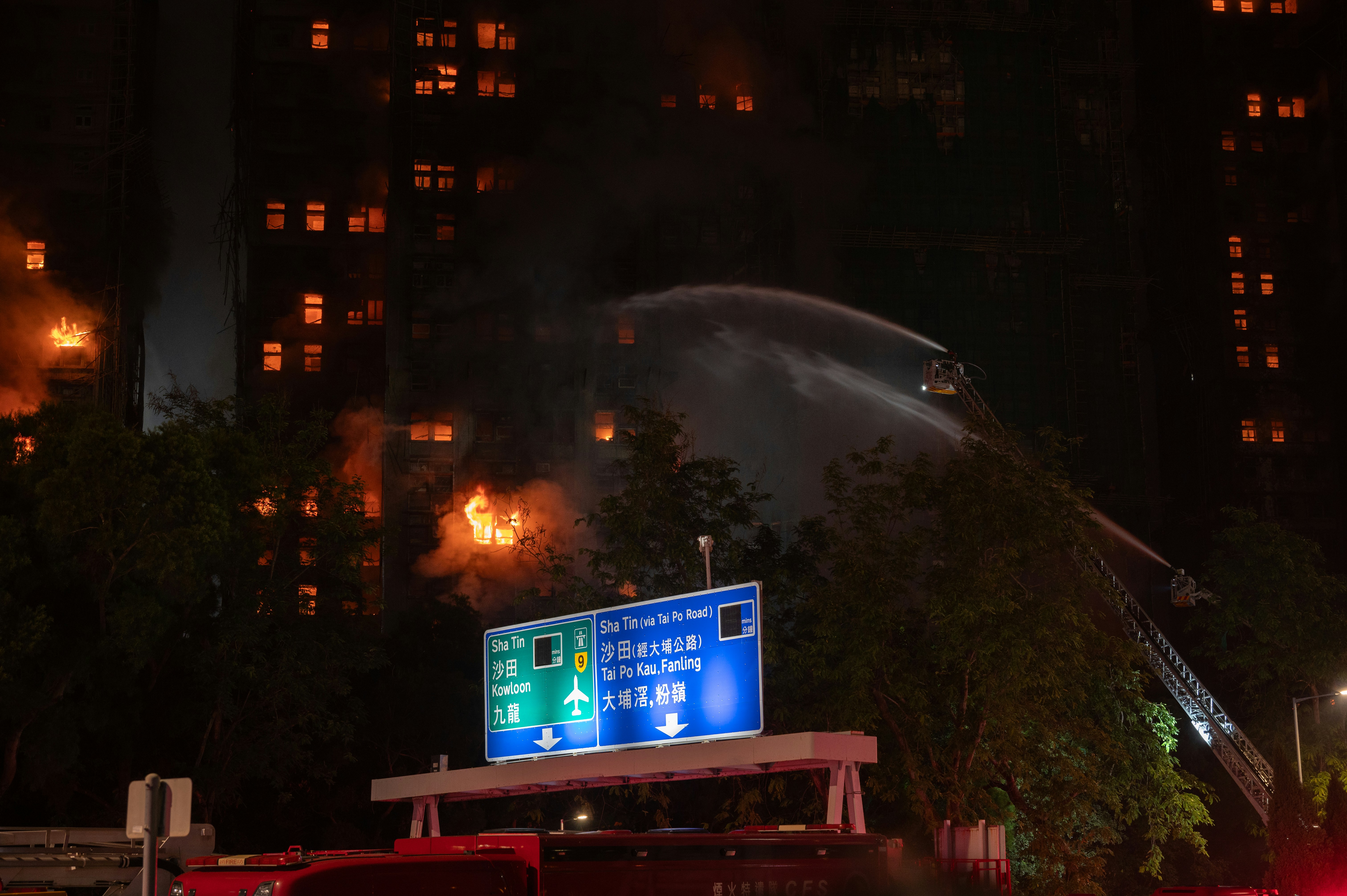 Firefighters battling a building fire at night with water.