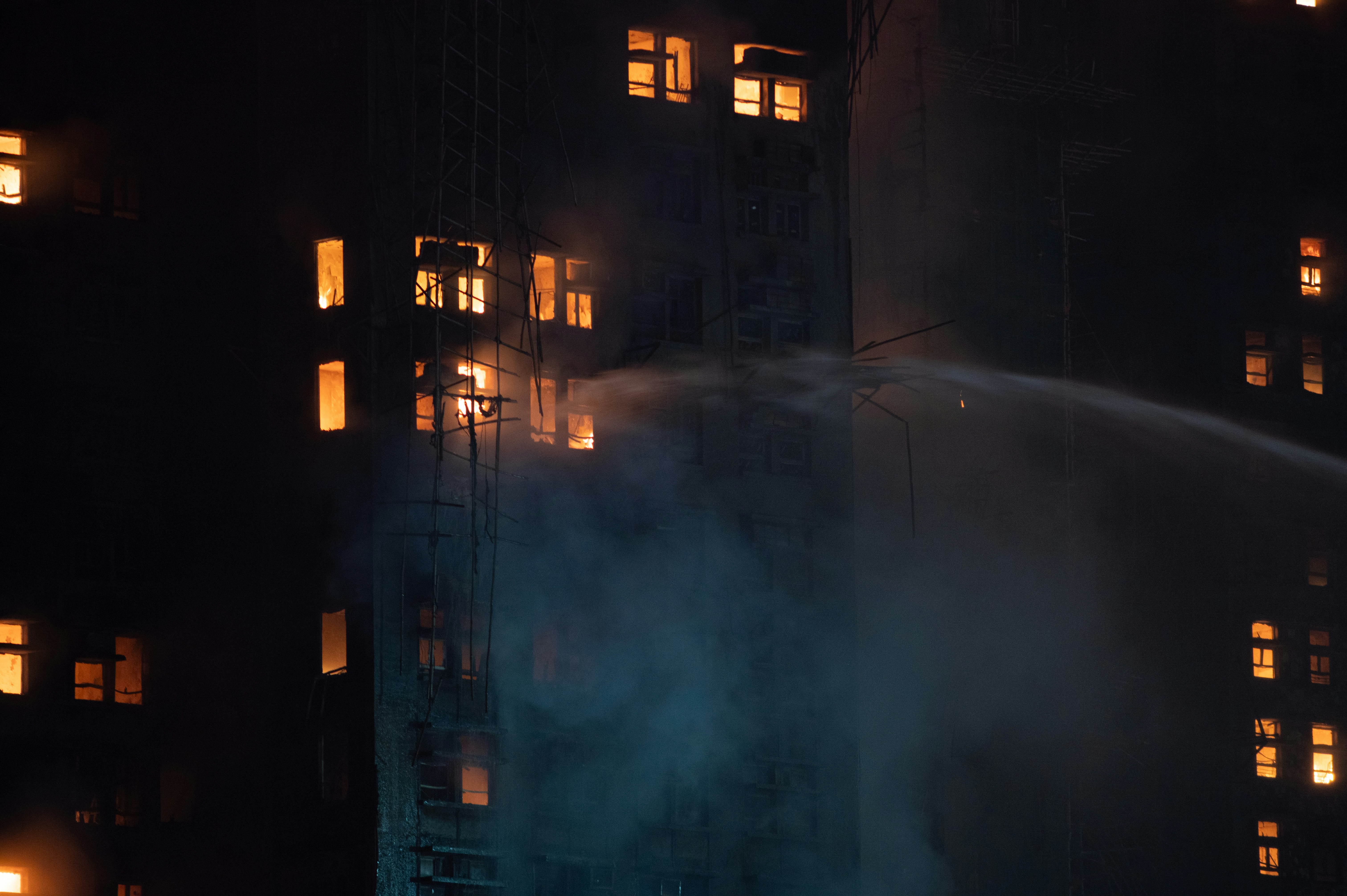 消防士たちは夜間に燃え盛る建物に水を噴射します。