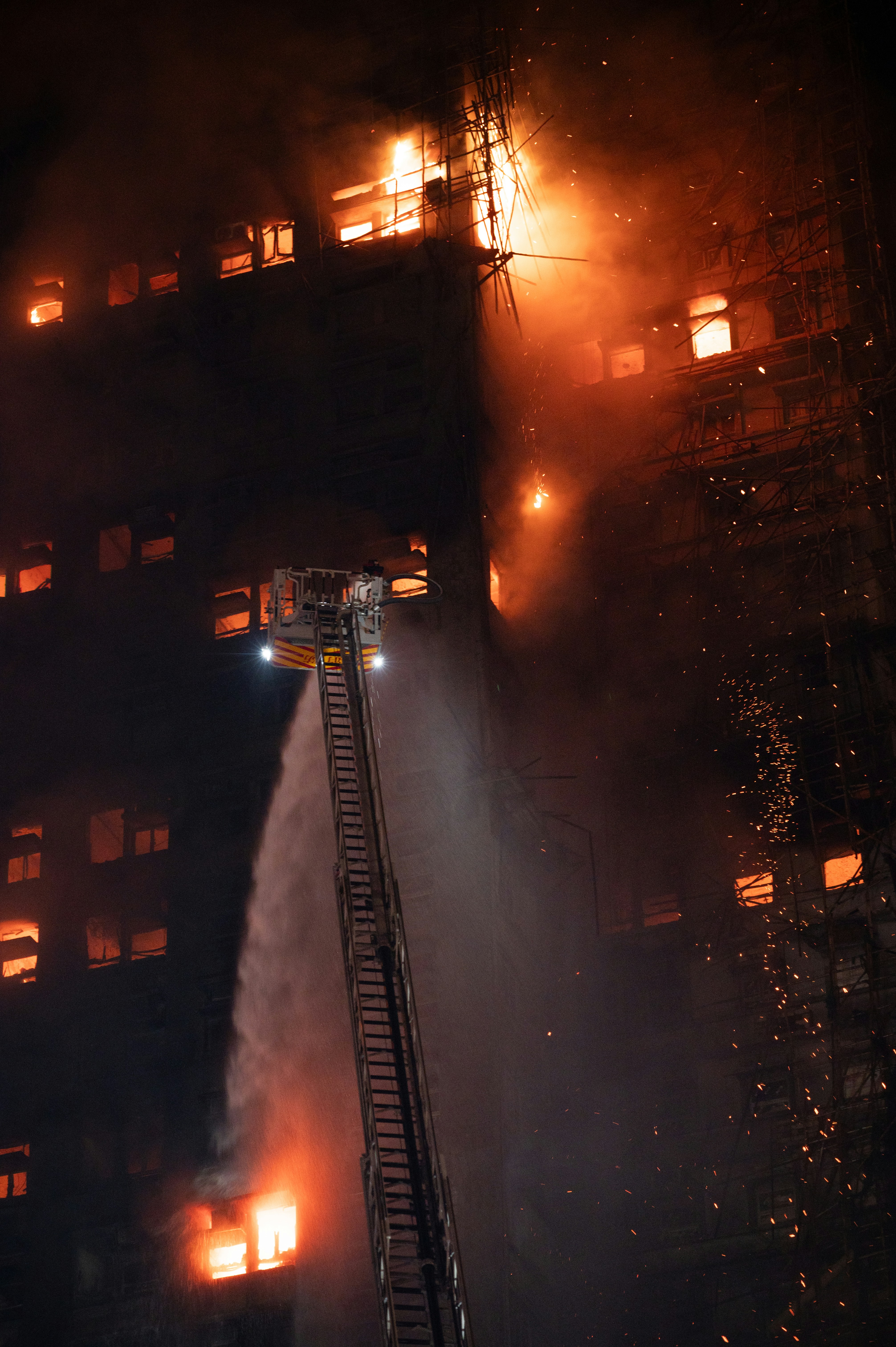 Bombeiros enfrentam um incêndio em um prédio à noite.