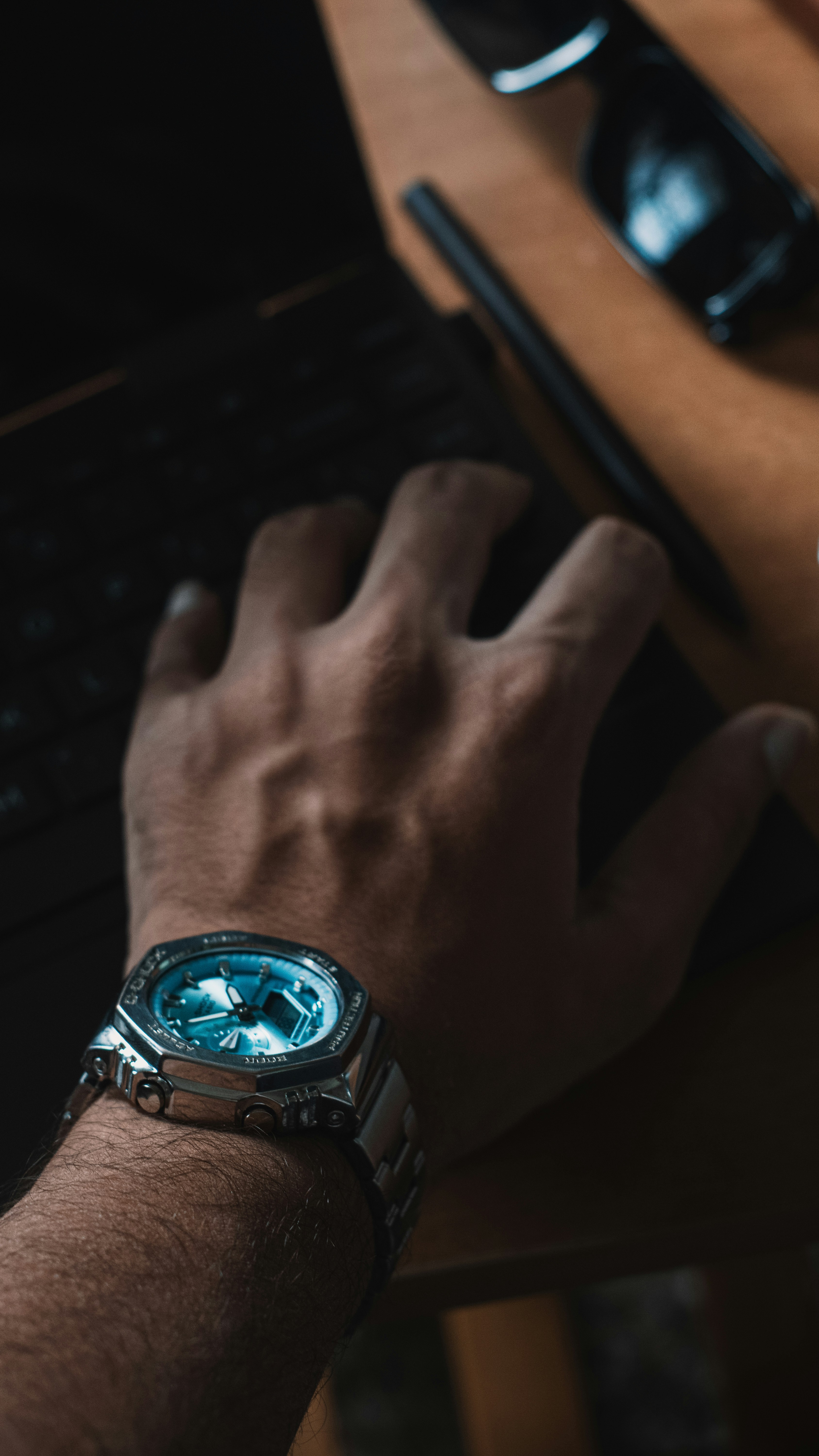 Man wearing a silver watch typing on keyboard.