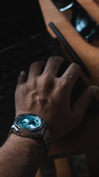 Man wearing a silver watch typing on keyboard.