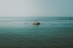 A small boat floats on the calm blue ocean