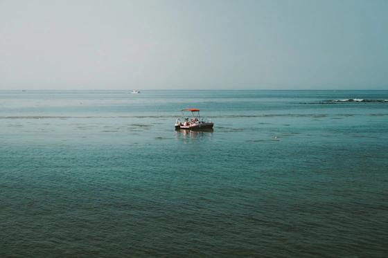 A small boat floats on the calm blue ocean