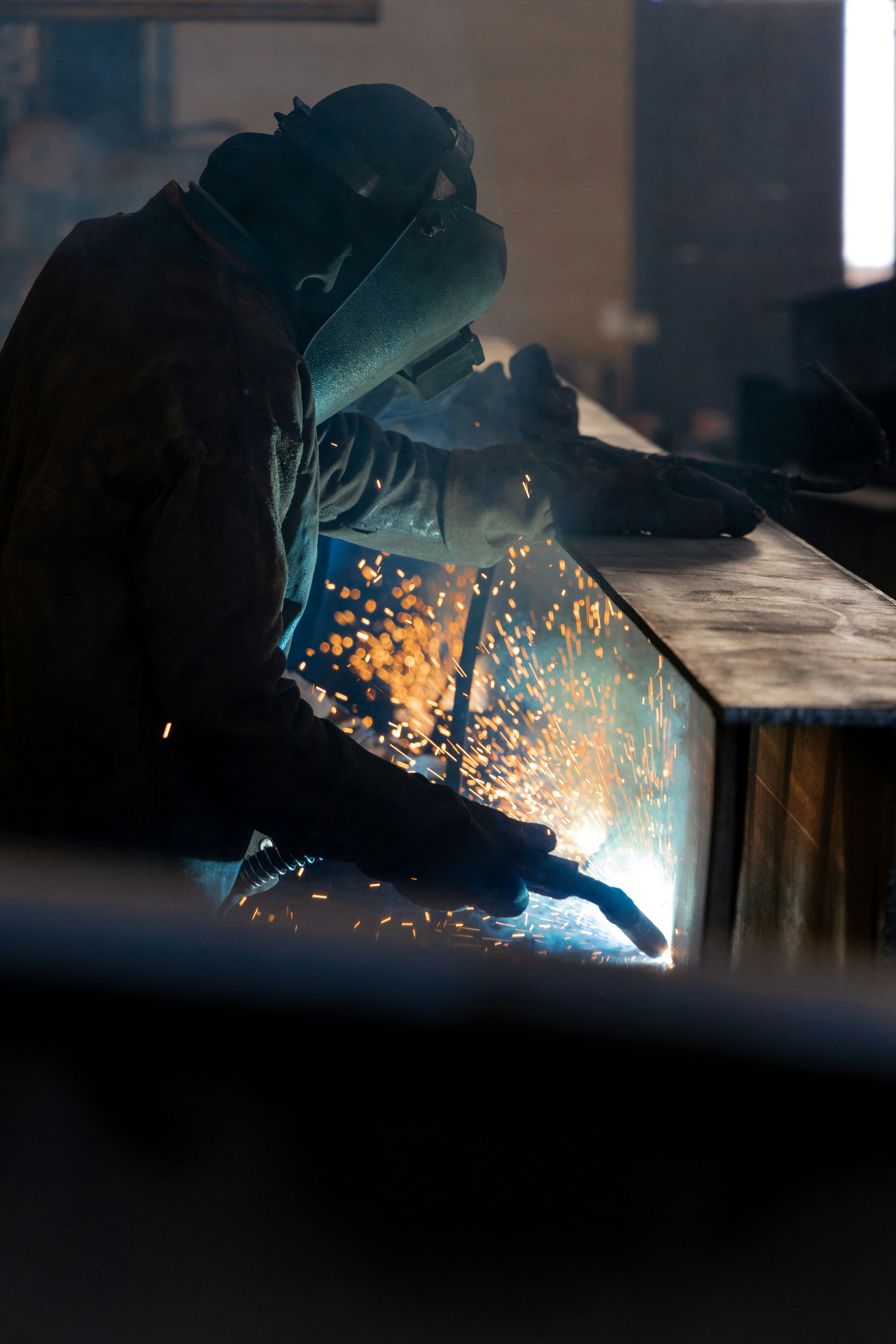 Welder working with sparks flying in workshop