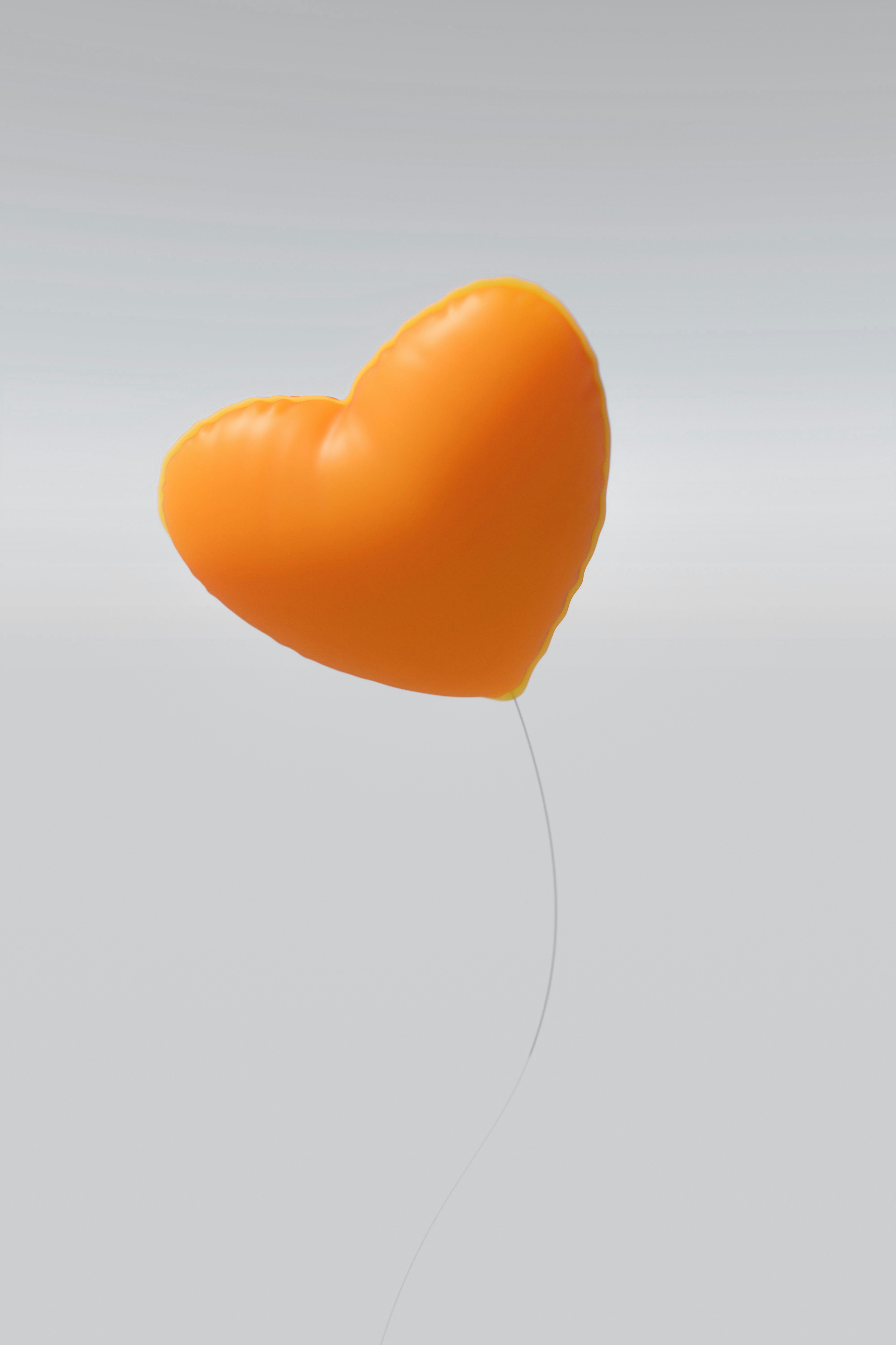 An orange heart-shaped balloon floats against a gray background.
