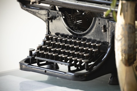 Close-up of an antique typewriter with a vase.