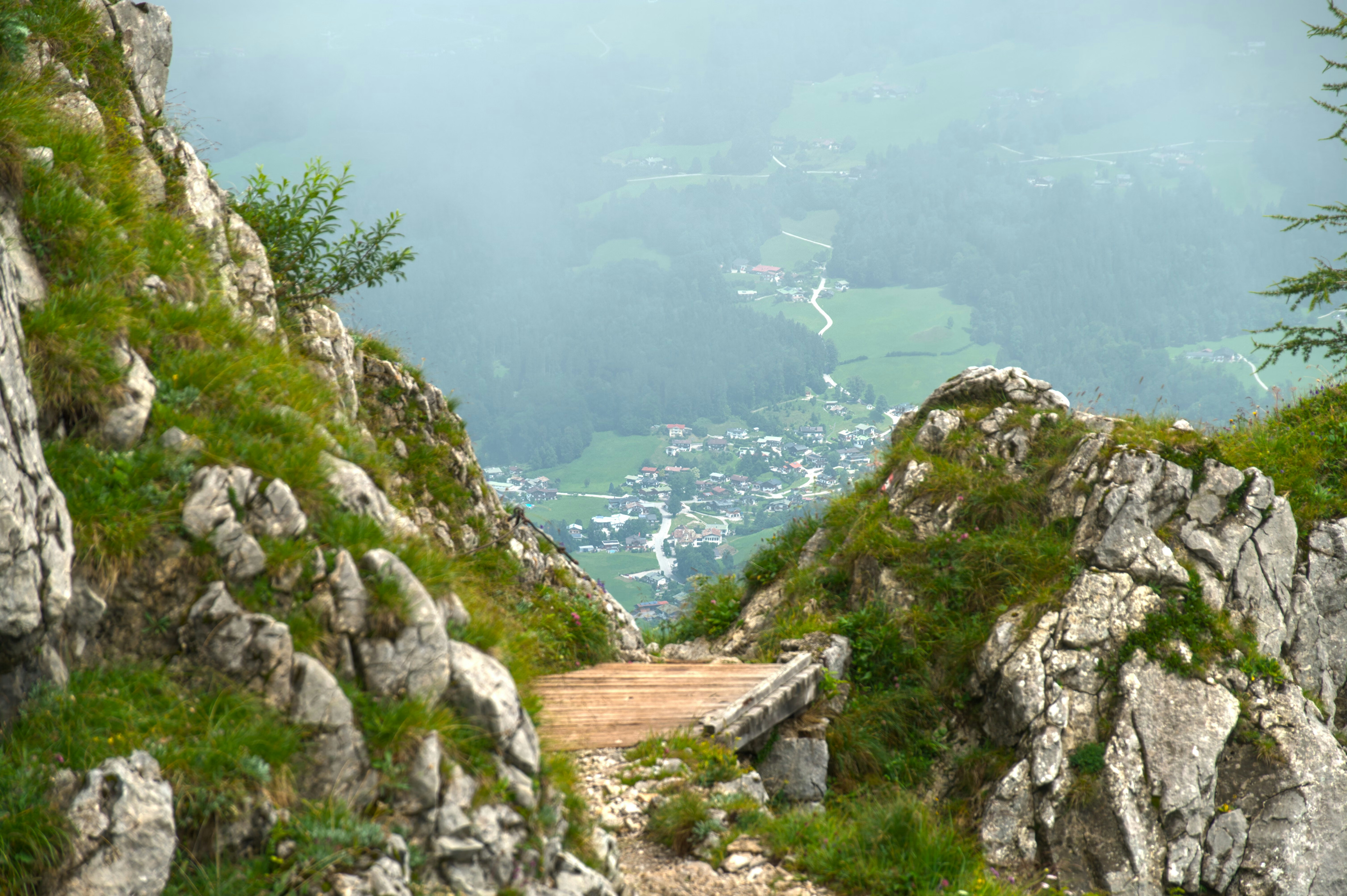 Rocky mountain path overlooking a green valley village
