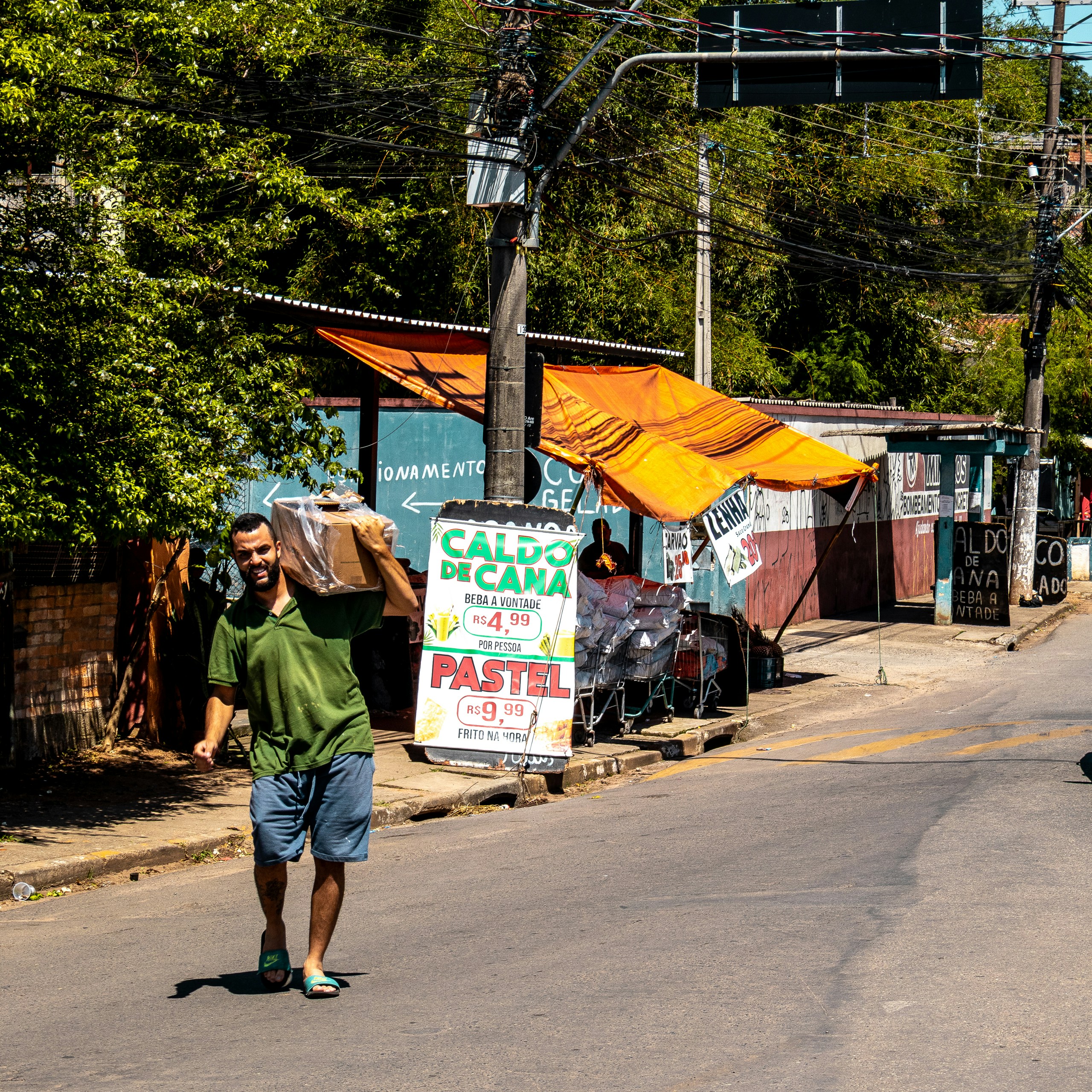 Man carries box on shoulder down street.
