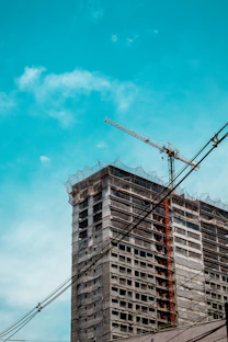 Construction crane on unfinished building under blue sky