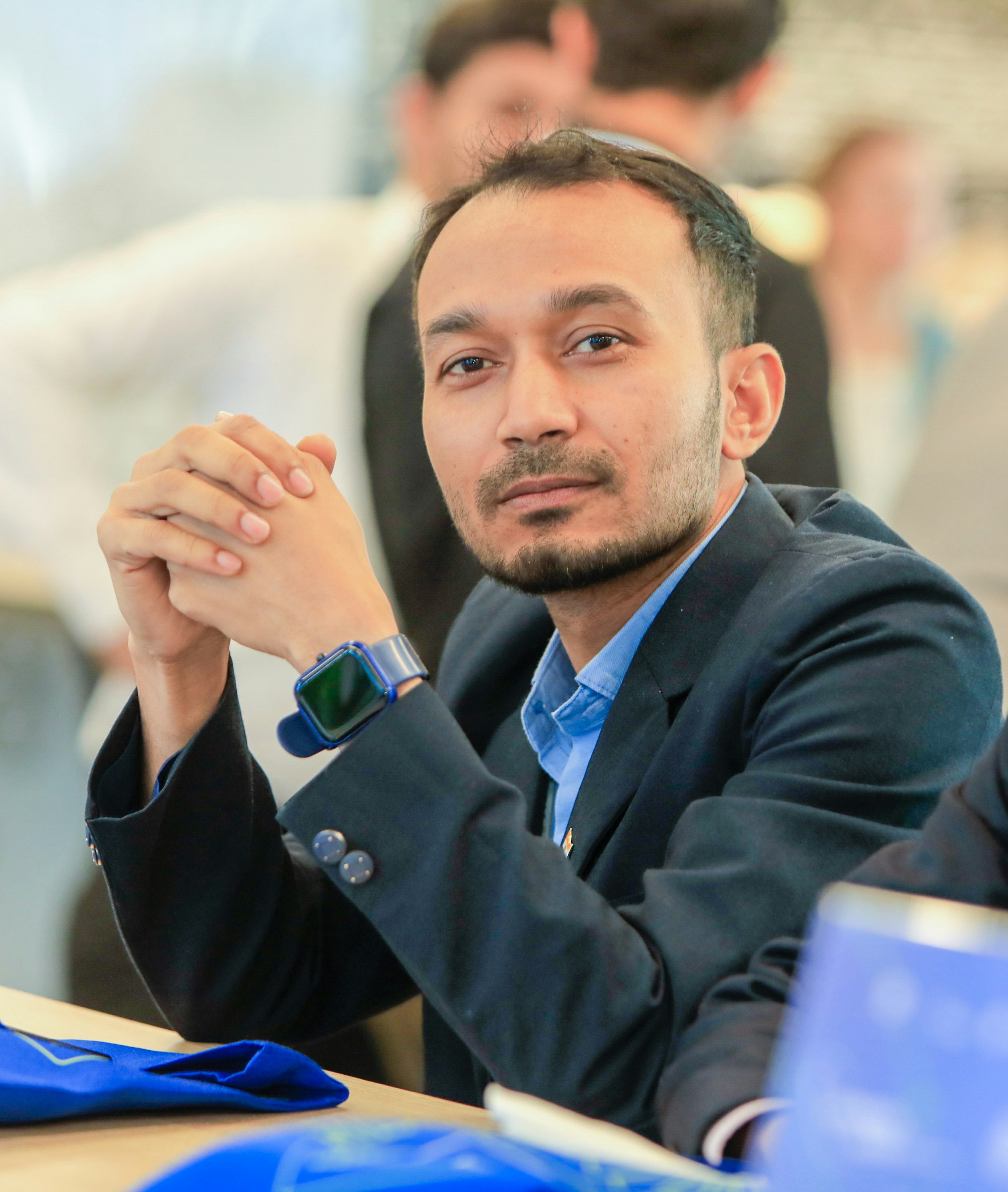Man wearing a suit and watch looking forward.