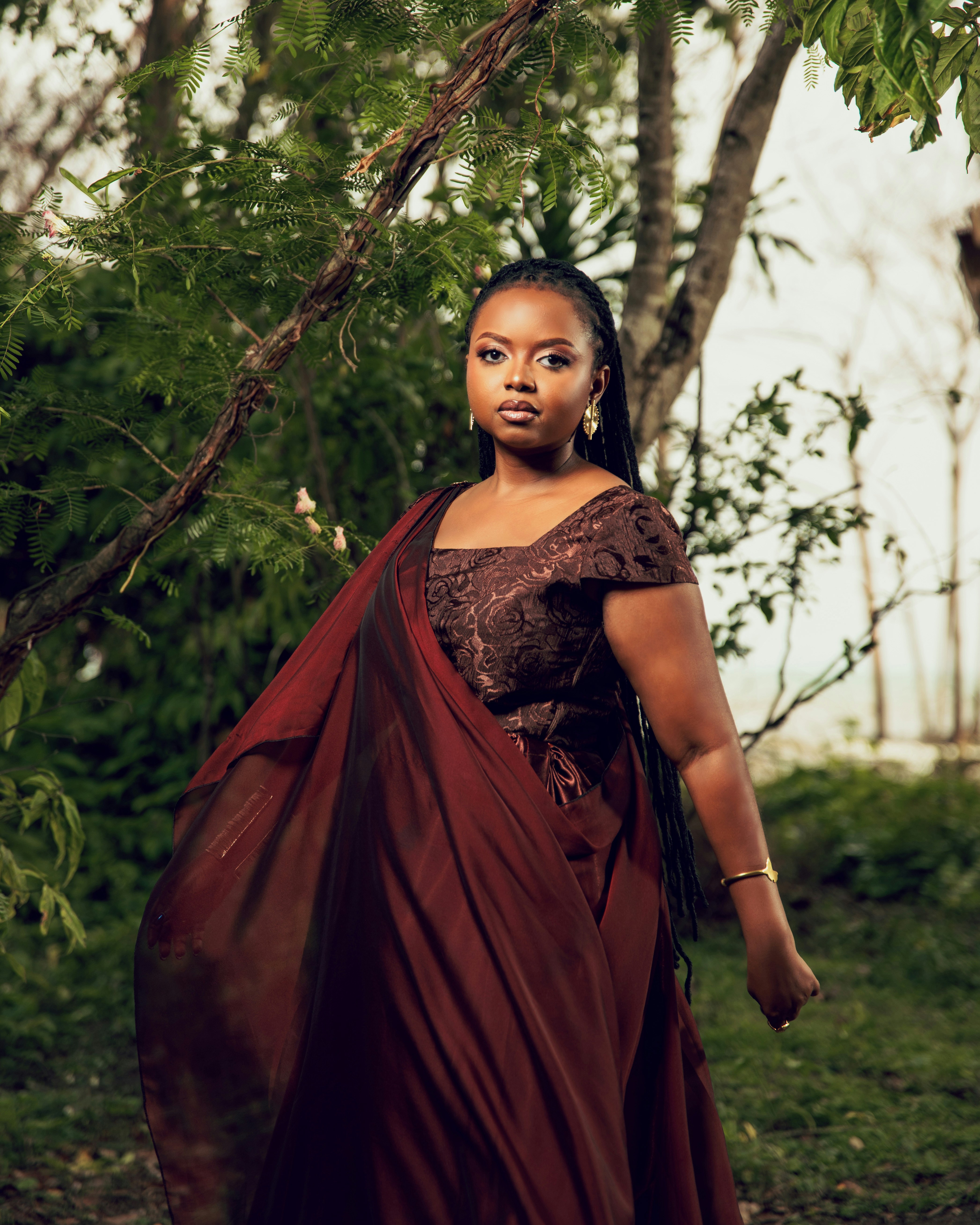 A young woman in a dark red dress outdoors.