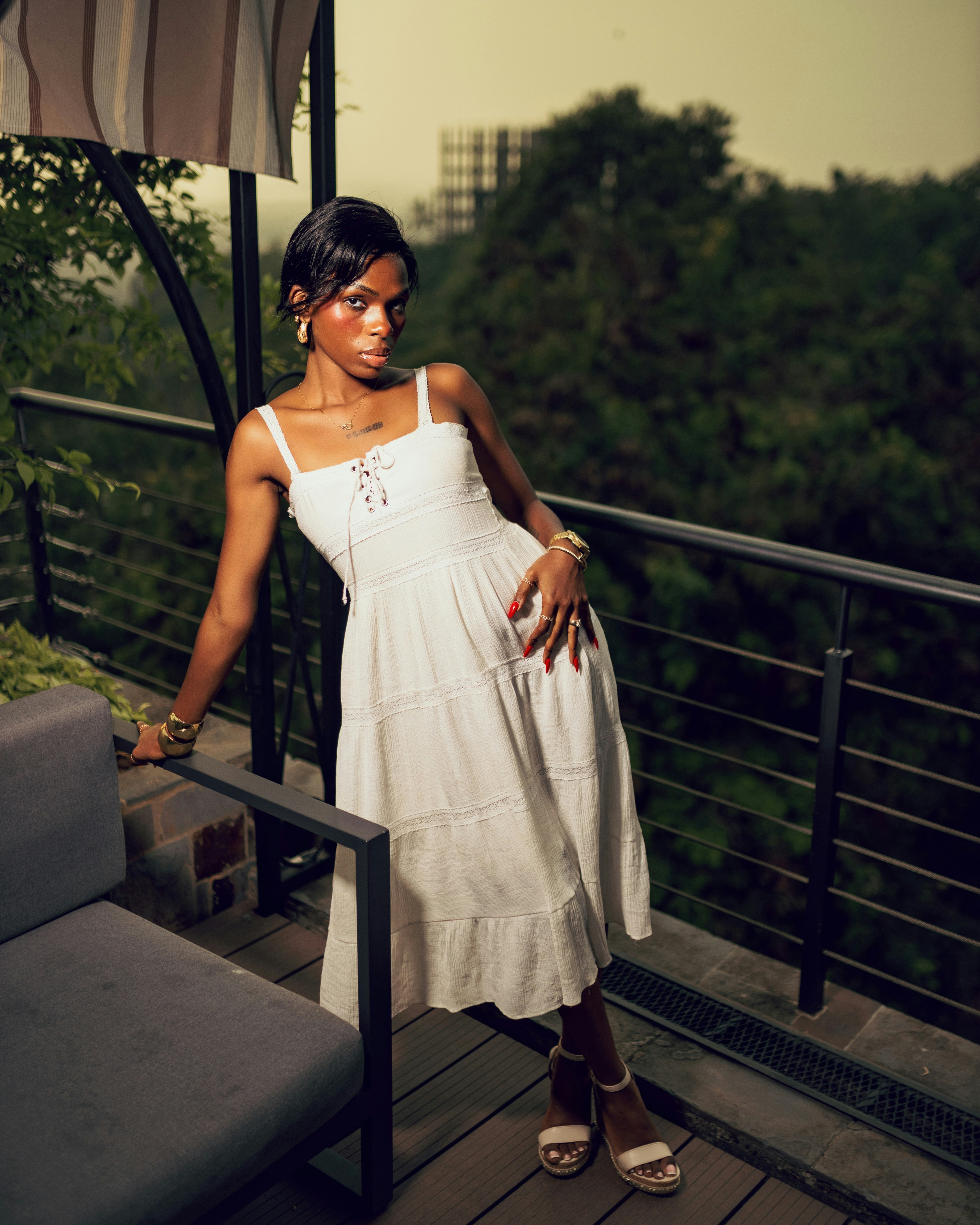 A woman in a white dress on a balcony.