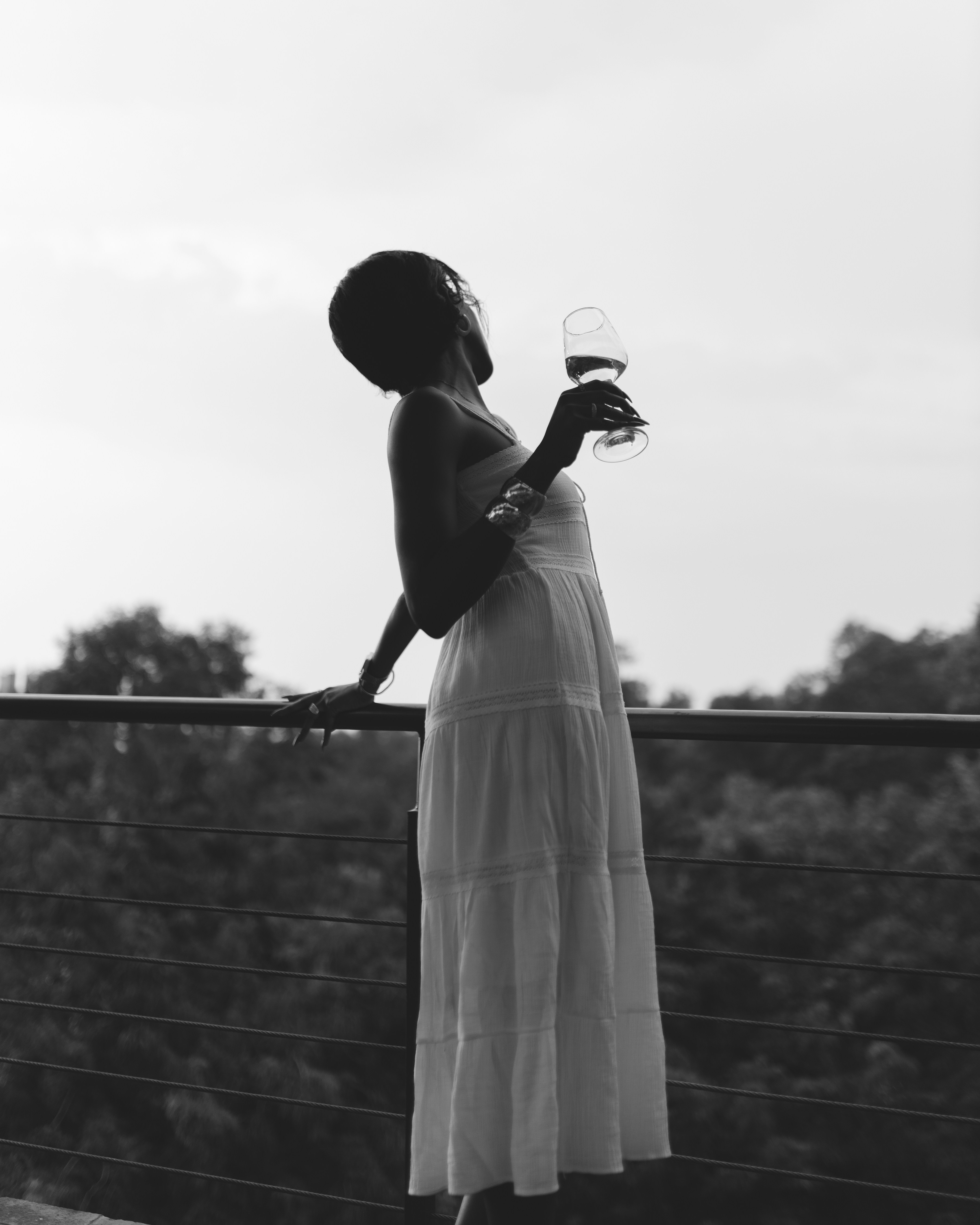 Woman in white dress holding wine glass on balcony