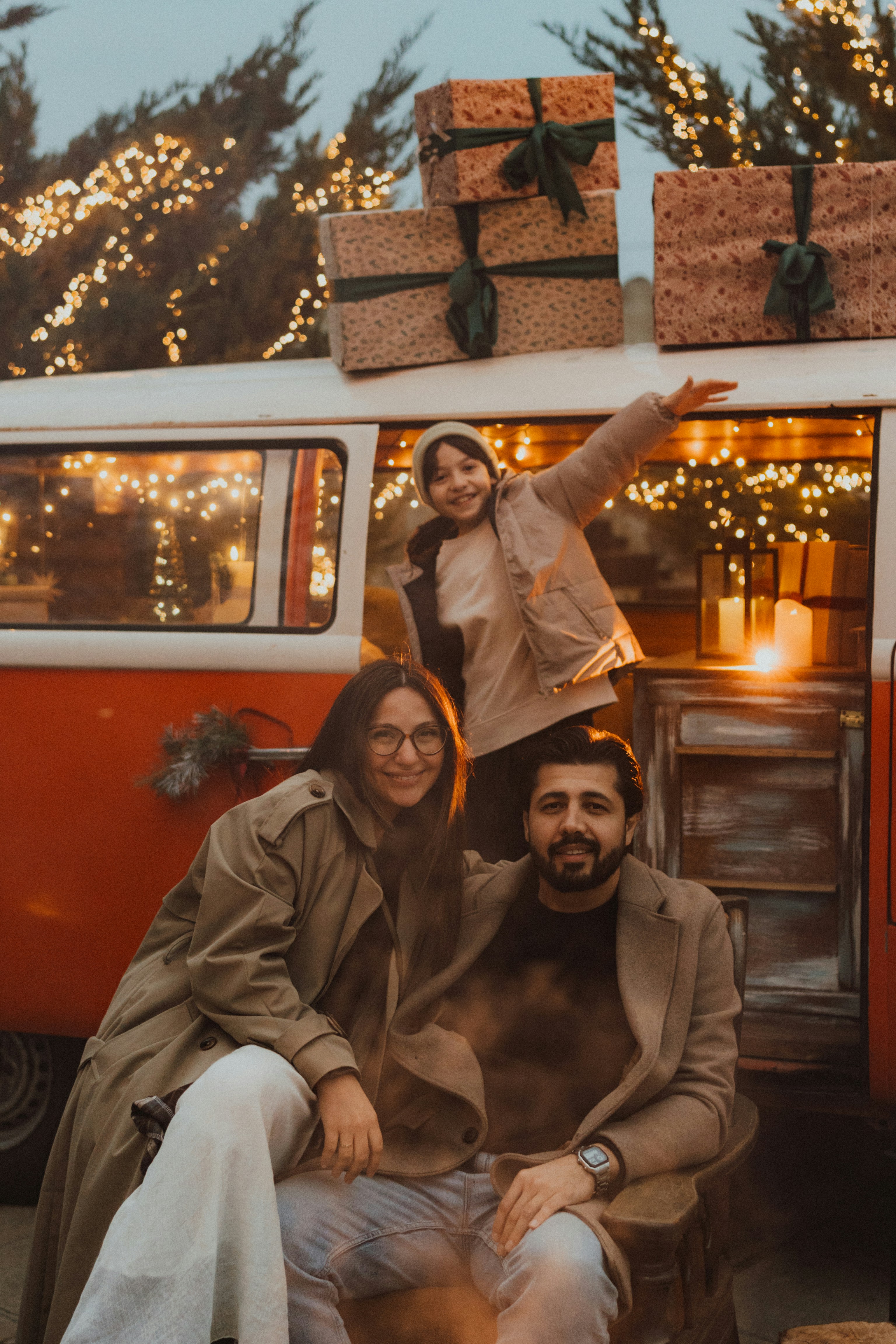 Family posing by a vintage van with christmas gifts.