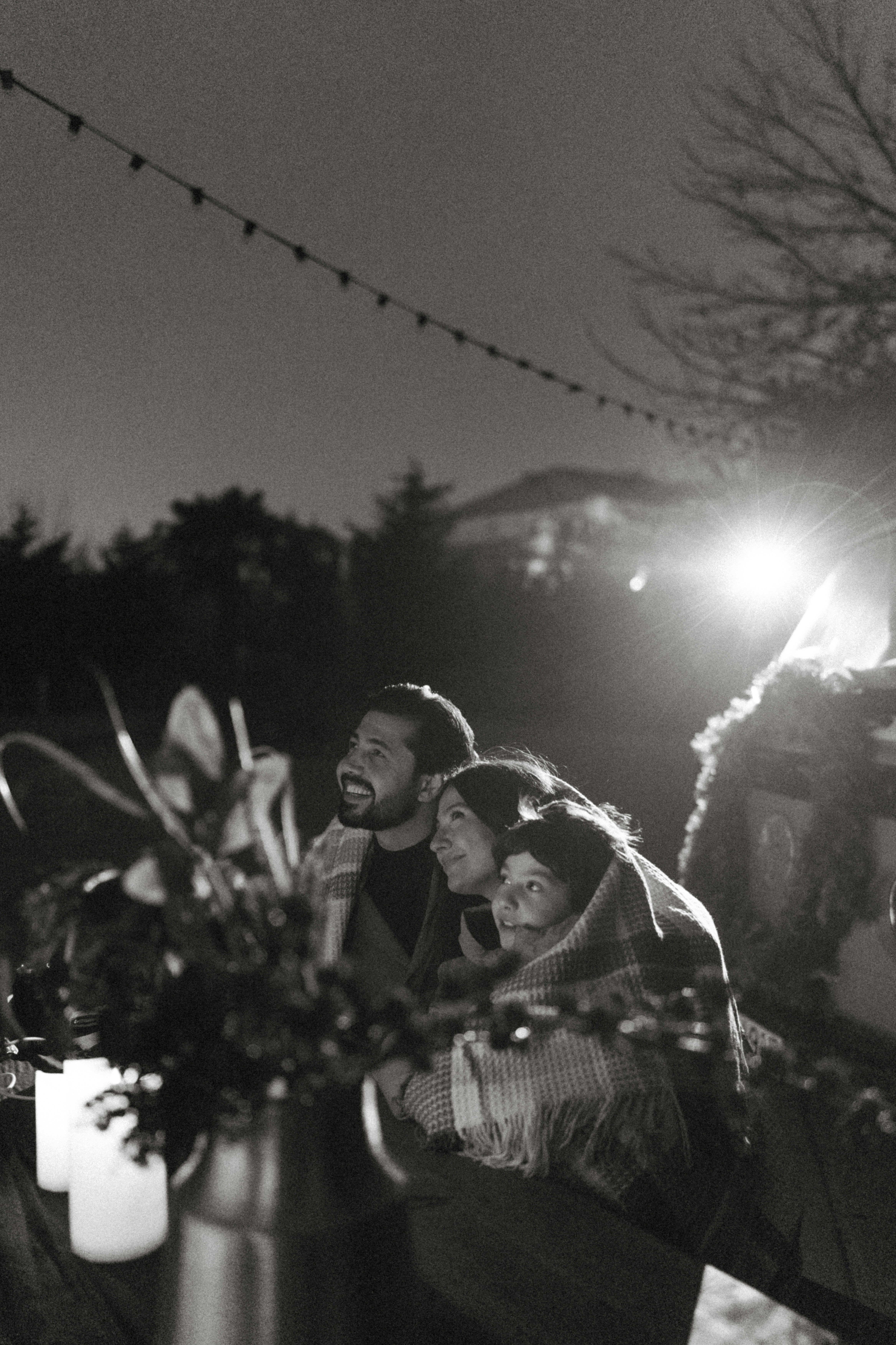 People gathered outdoors under string lights at night.