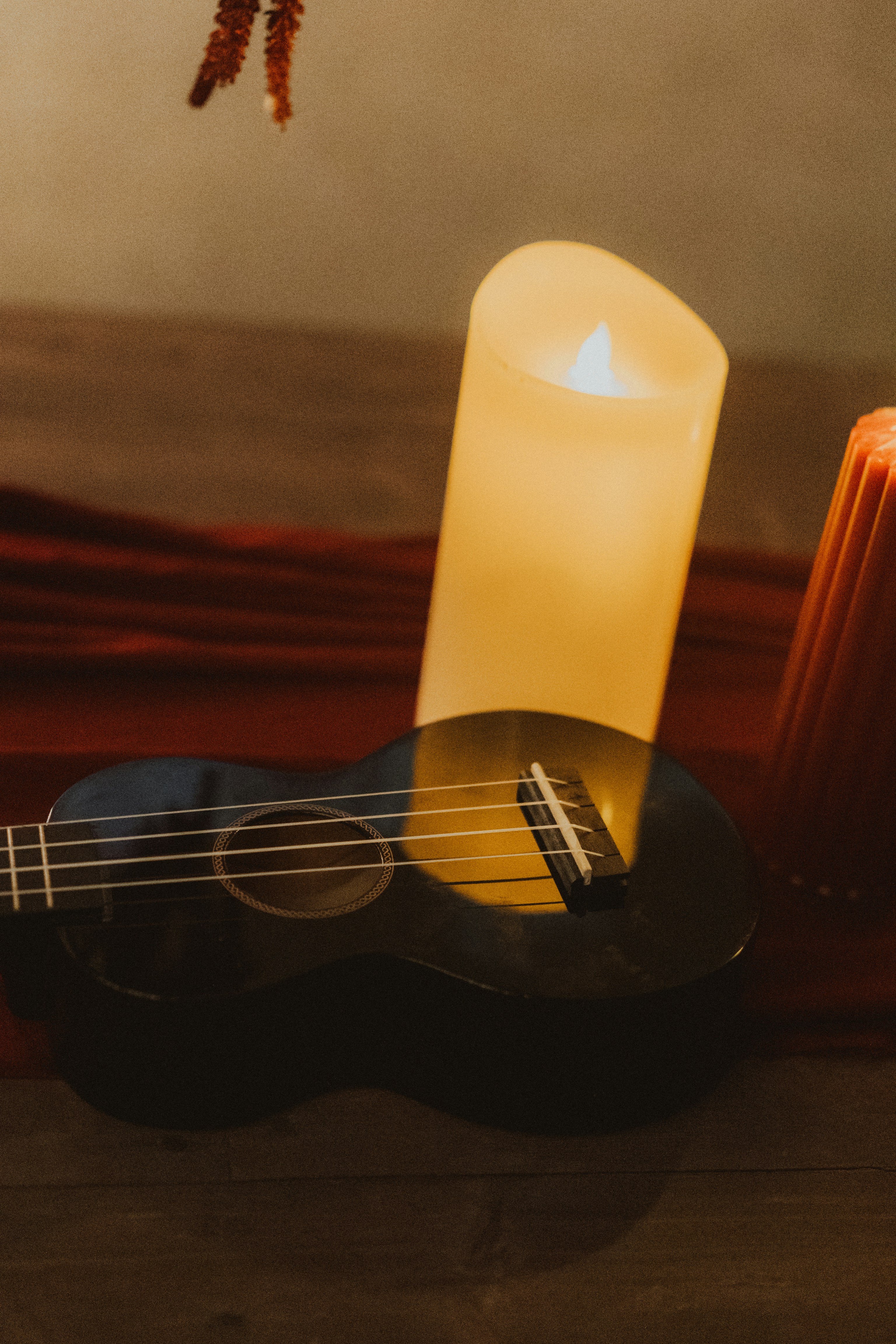Ukulele with a lit candle and red fabric