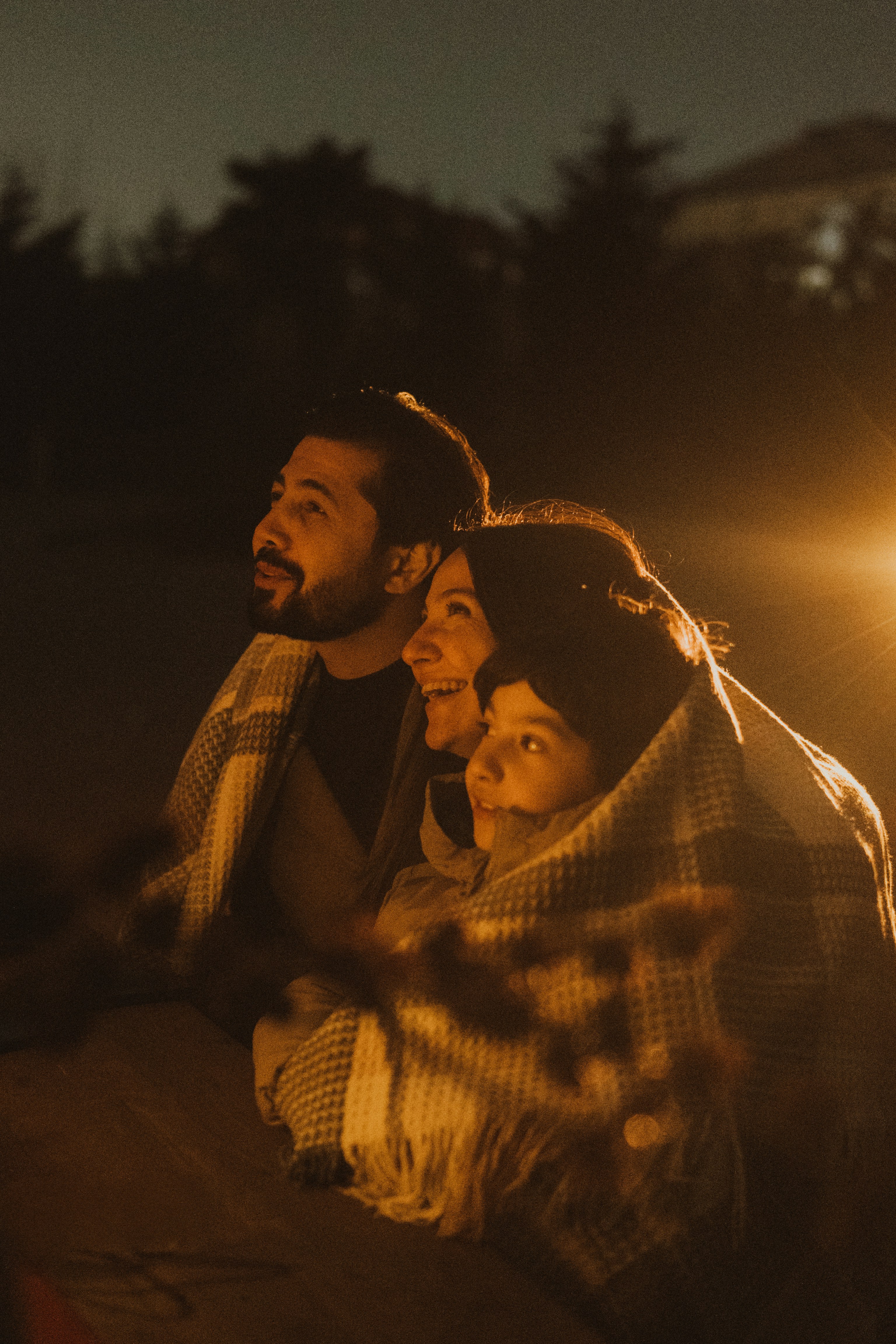 Family wrapped in blanket looking at night sky
