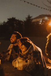 Family huddled together under blanket at night.