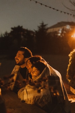 Family huddled together under blanket at night.