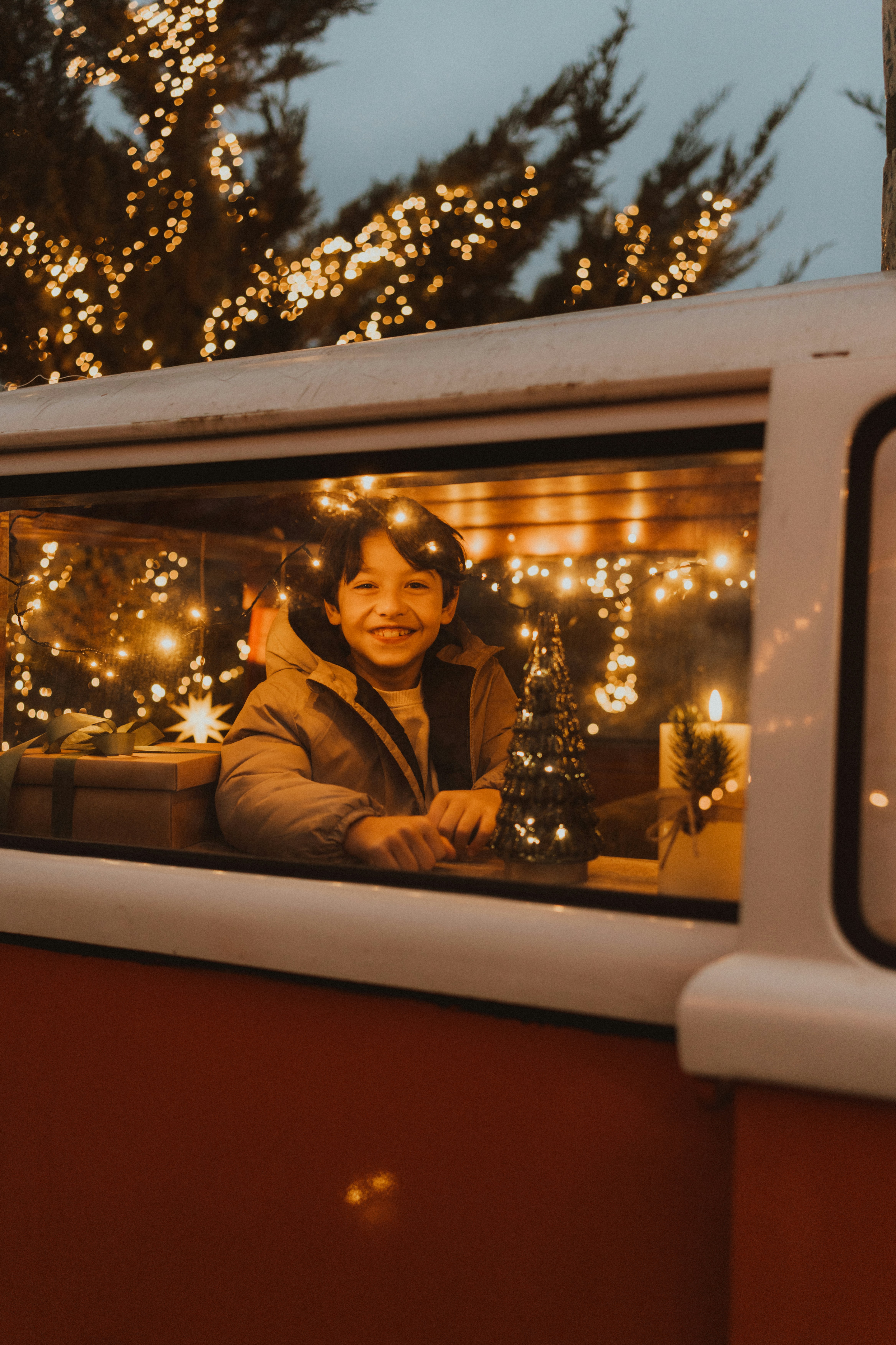 Smiling boy in a van decorated with christmas lights