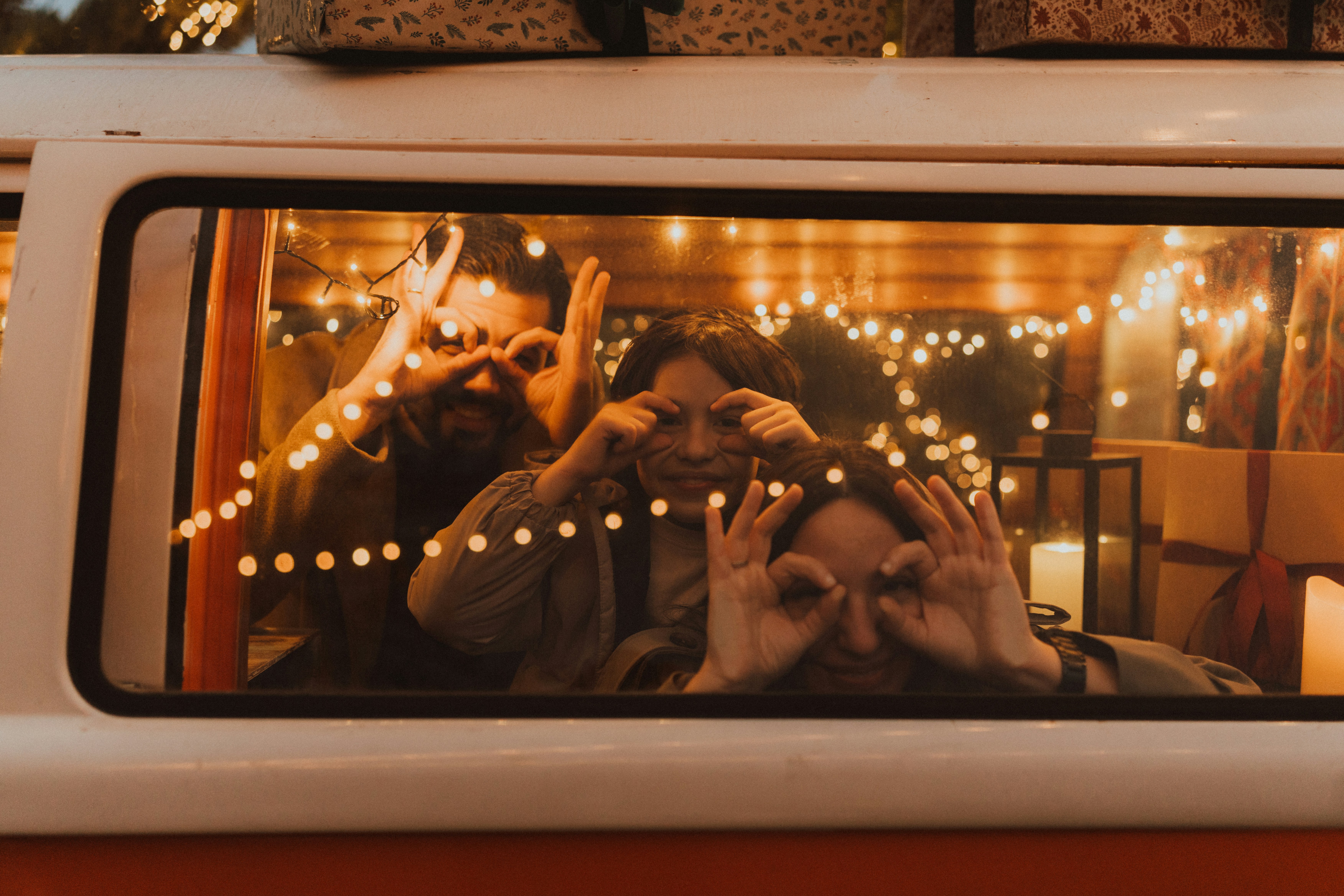 Three people making hand gestures through van window
